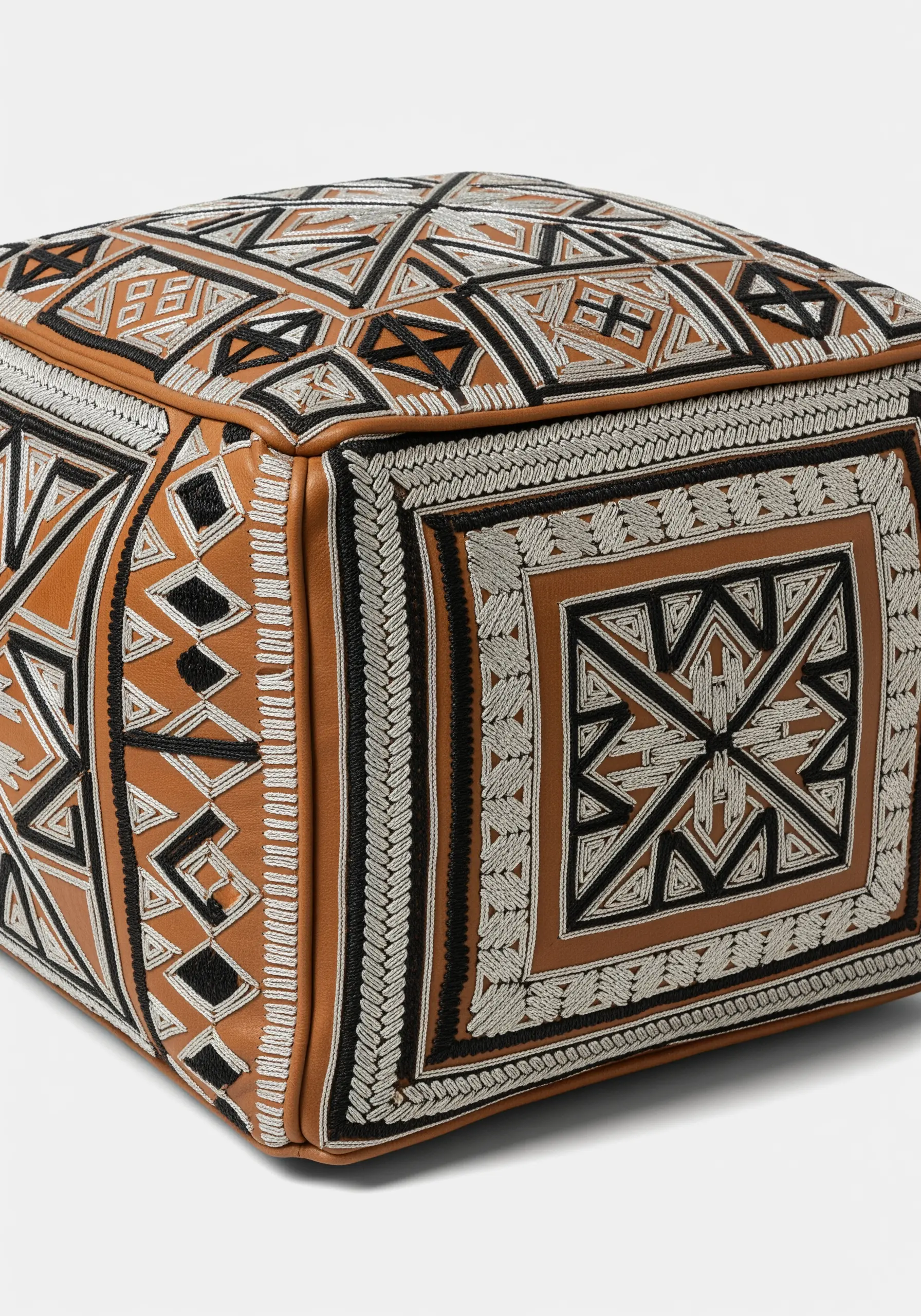 Geometric silver and black embroidery on a brown leather Moroccan pouf