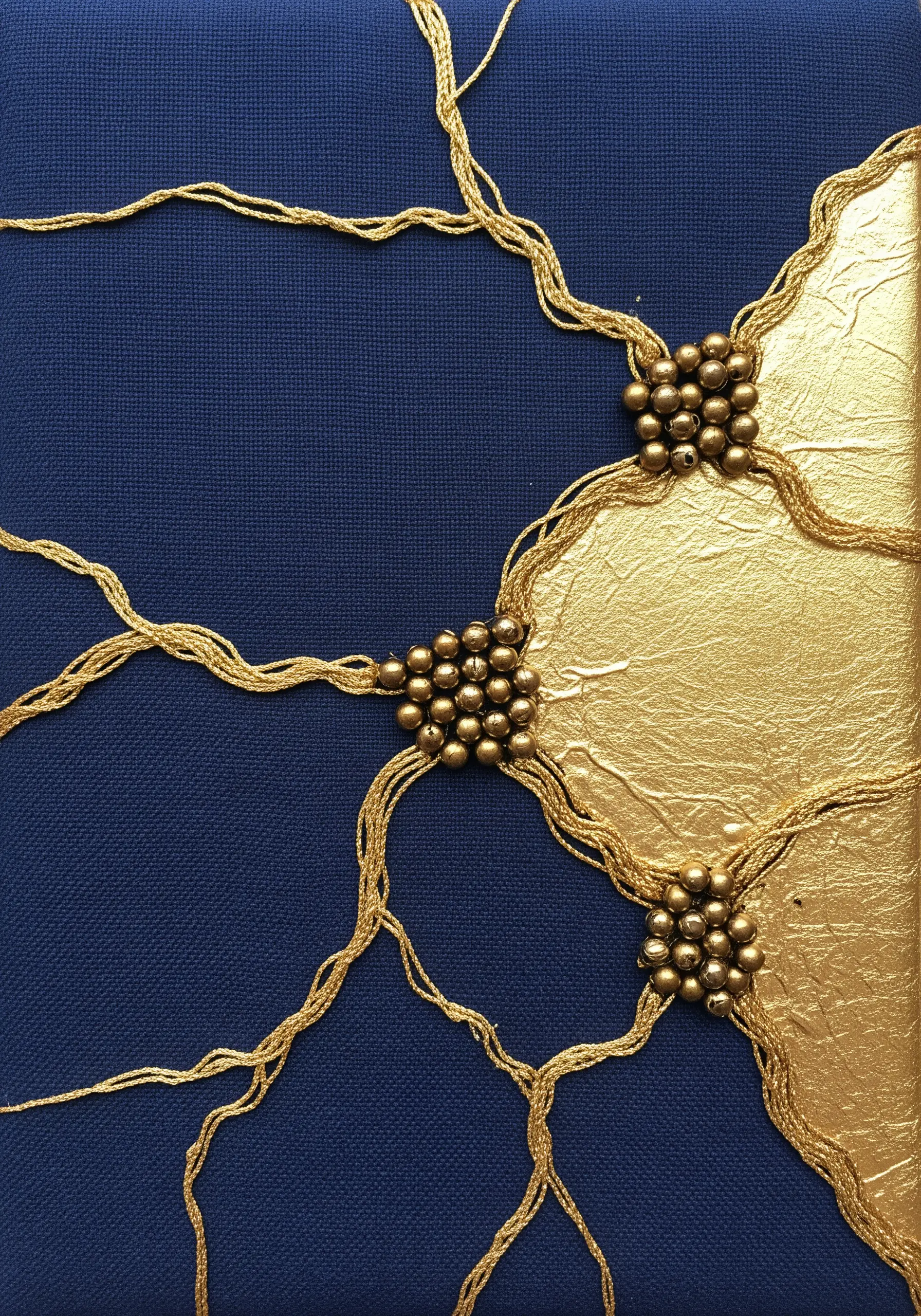 Kintsugi-style art on navy fabric with gold leaf, couched gold thread, and bead clusters.
