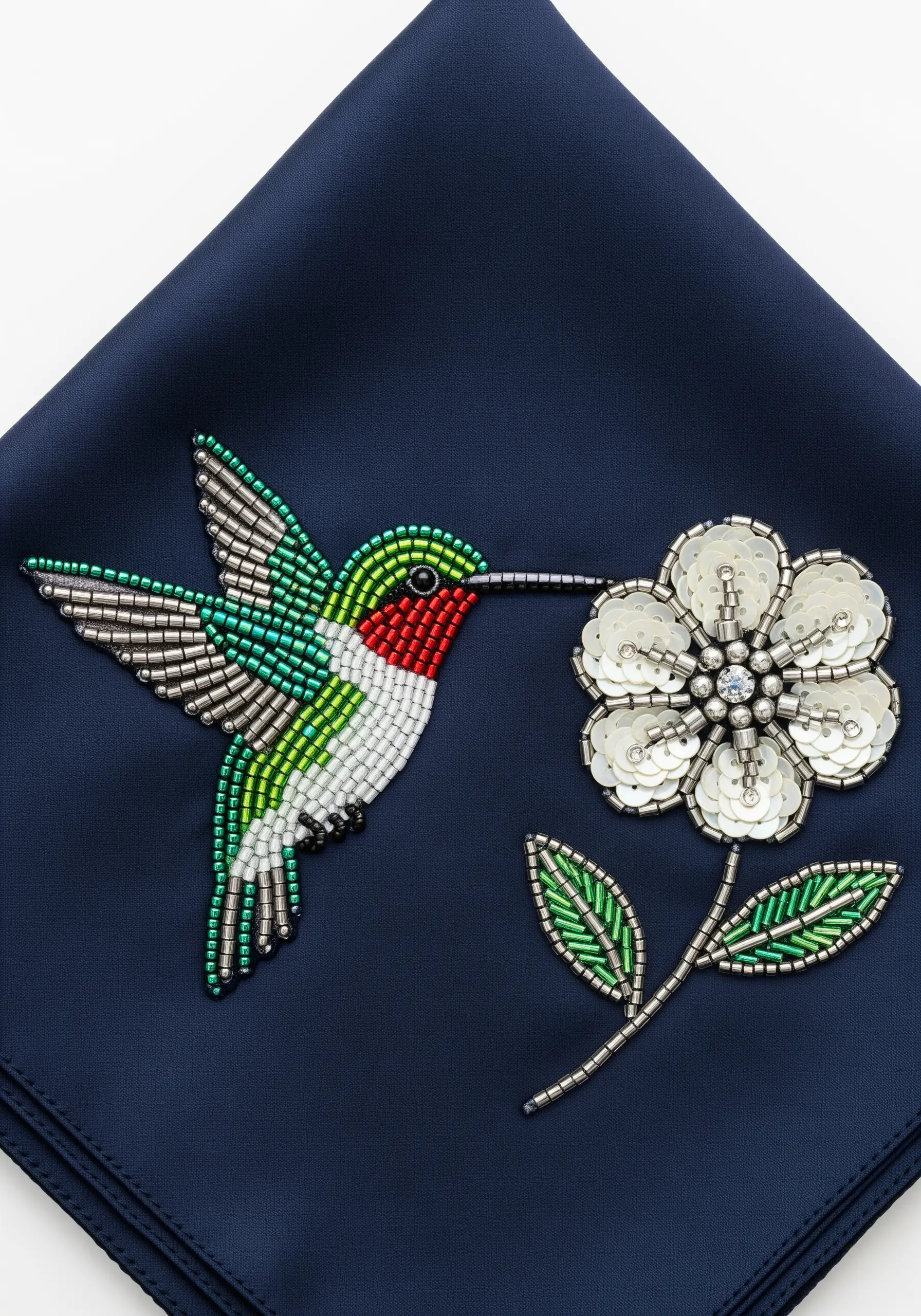 A hummingbird and flower made entirely of green, silver, and white beads and sequins.