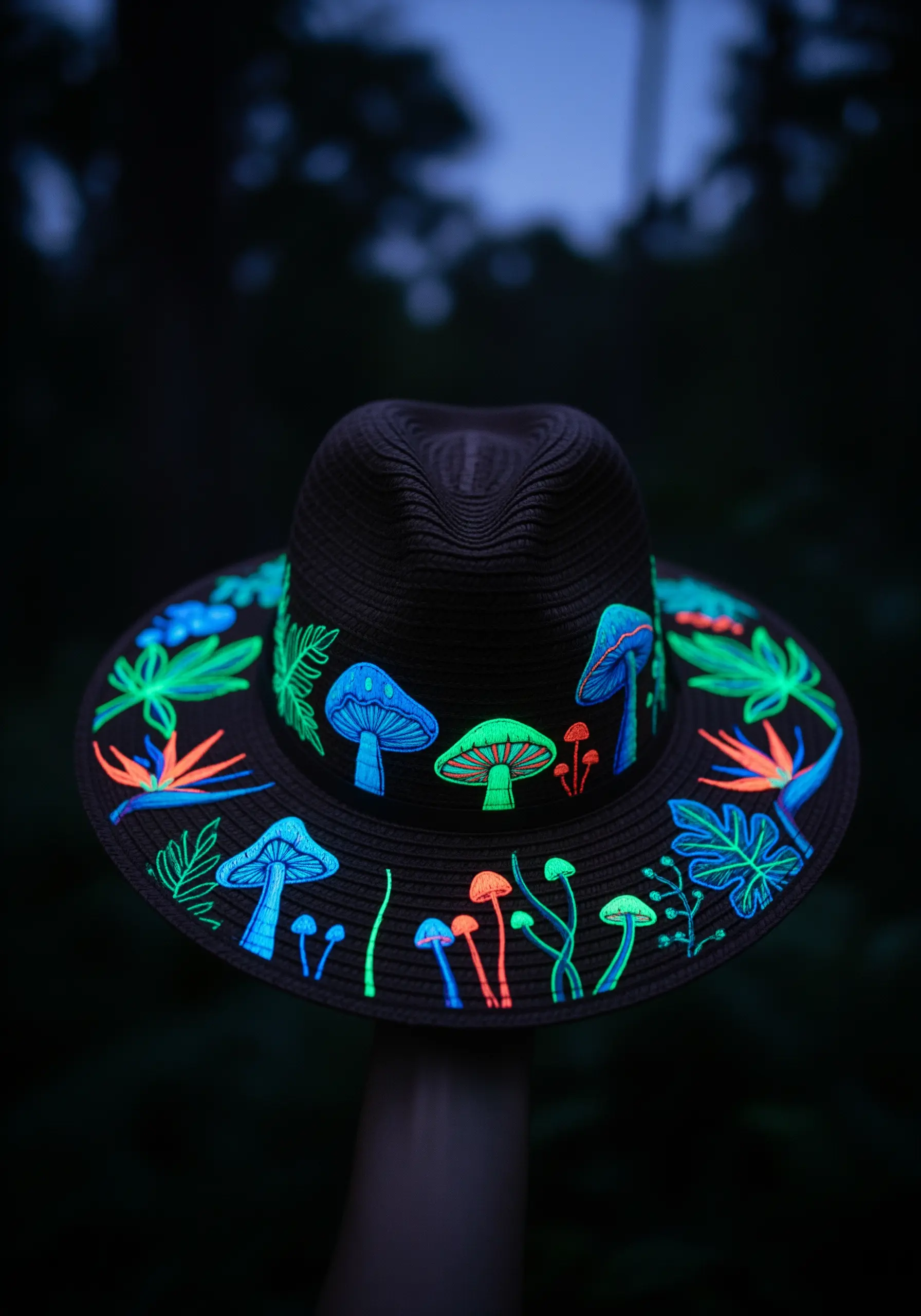Neon and glow-in-the-dark embroidered mushrooms and leaves on a black fedora hat.