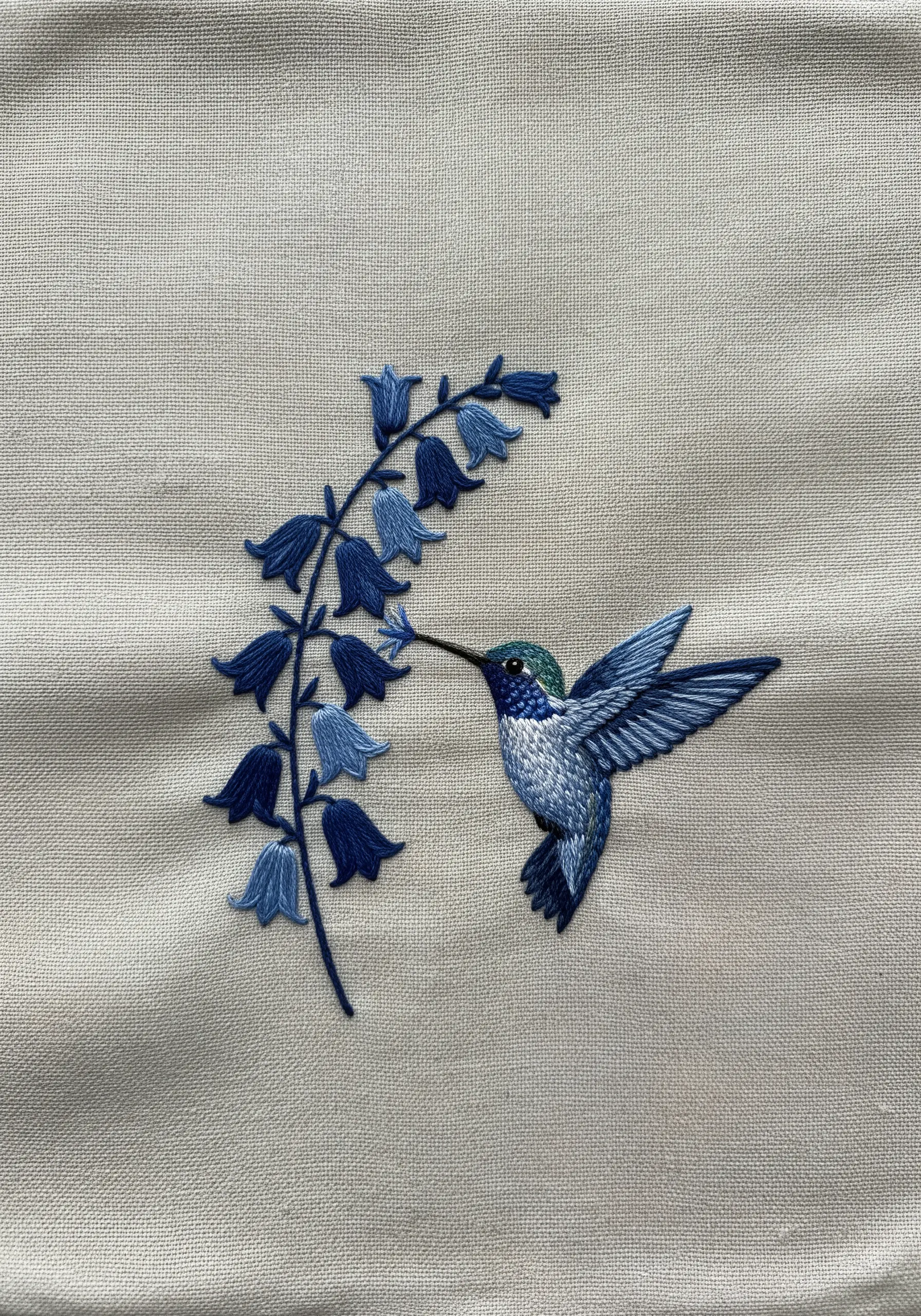 A blue hummingbird and bluebell flowers embroidered in shades of blue.