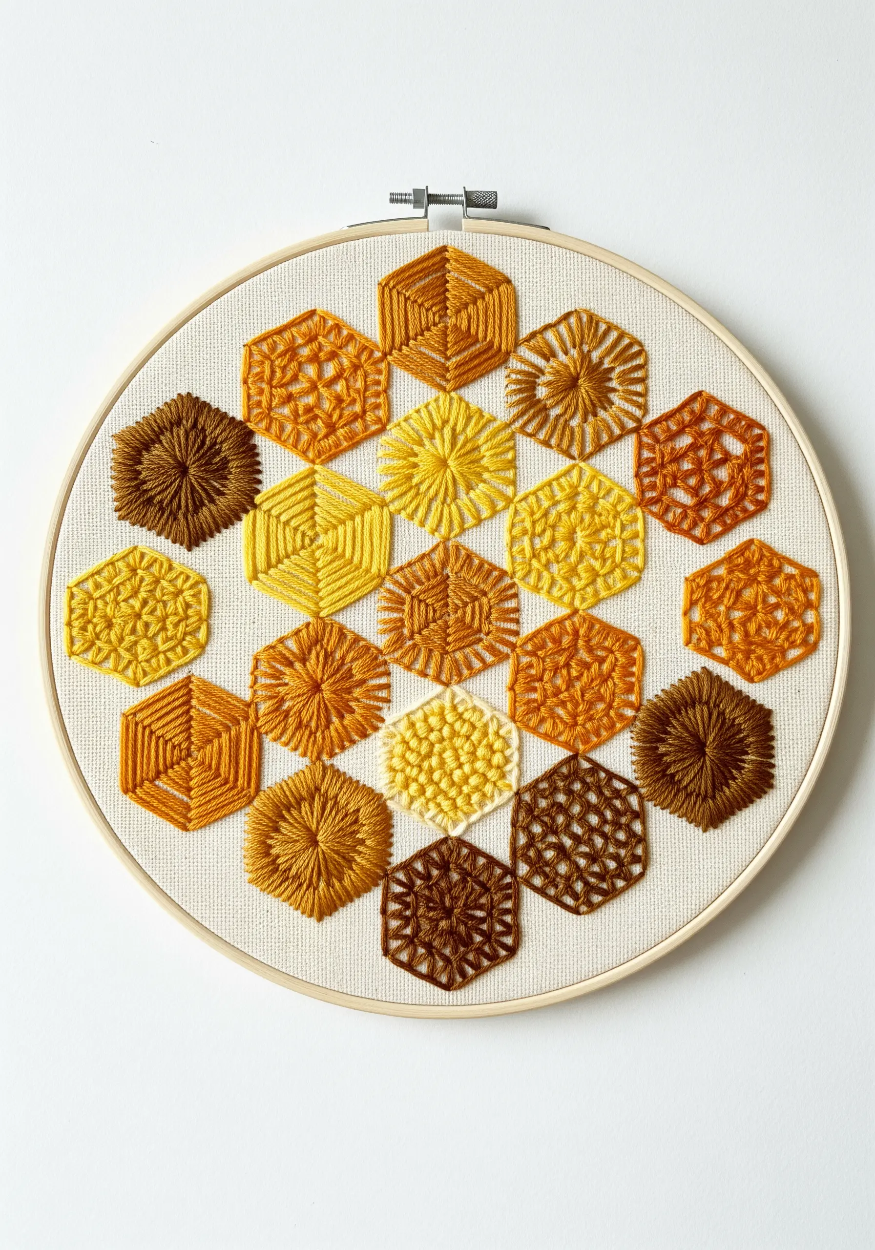 A geometric honeycomb pattern stitched with a gradient of naturally dyed yellow and brown threads.