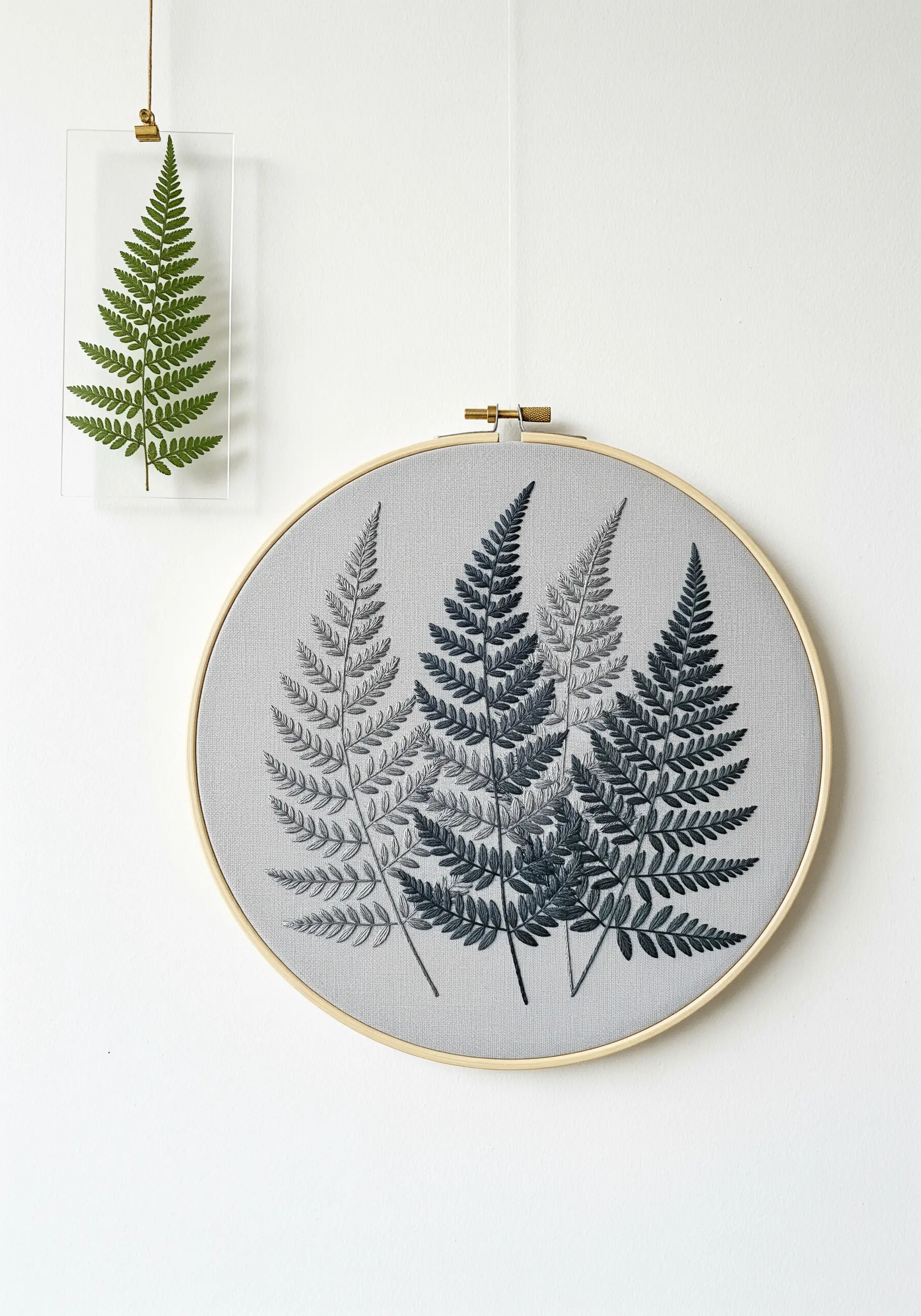 Four embroidered ferns in a gradient of grey tones on light grey fabric.