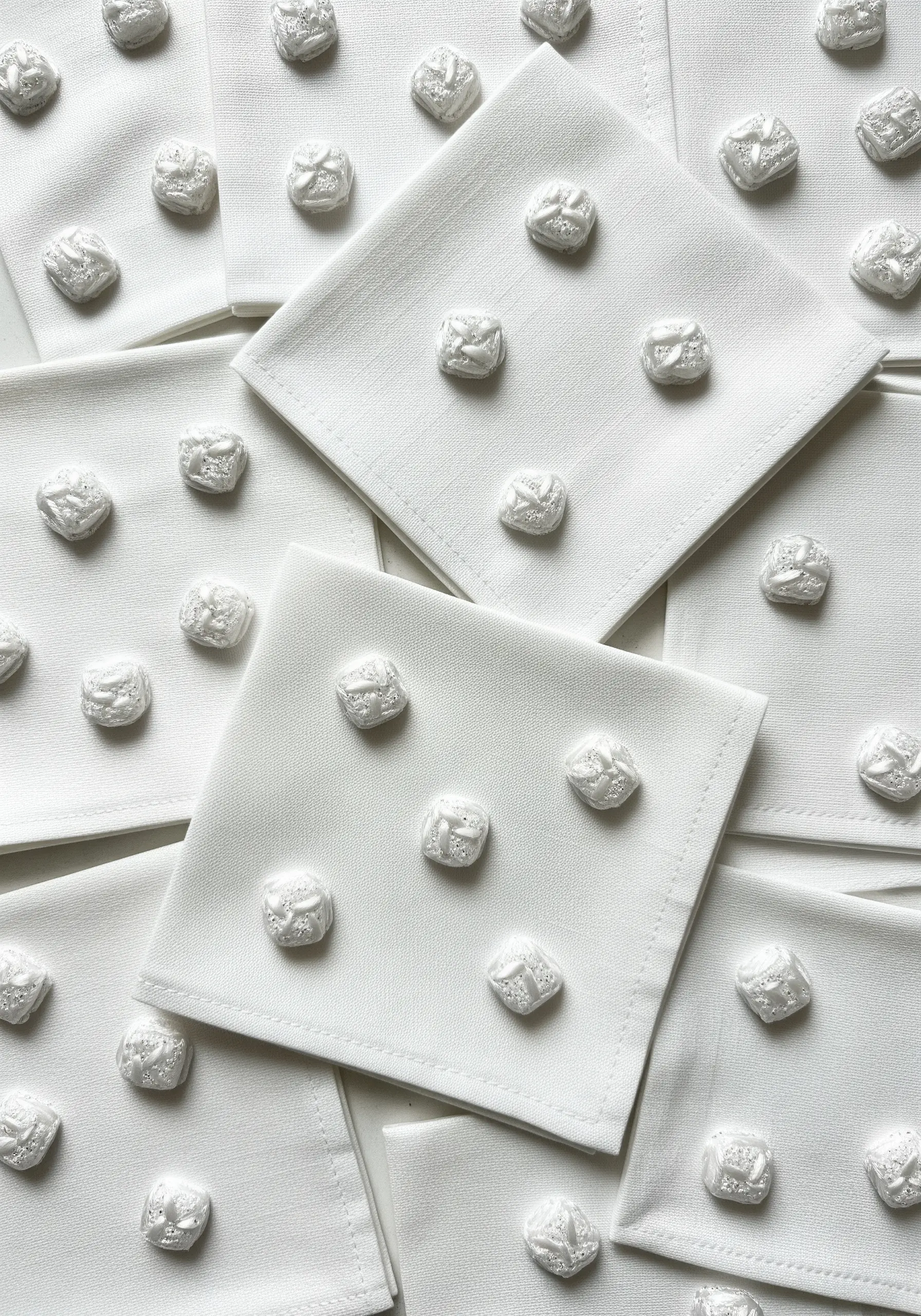 White napkins with raised, textured embroidered squares in a grid pattern.