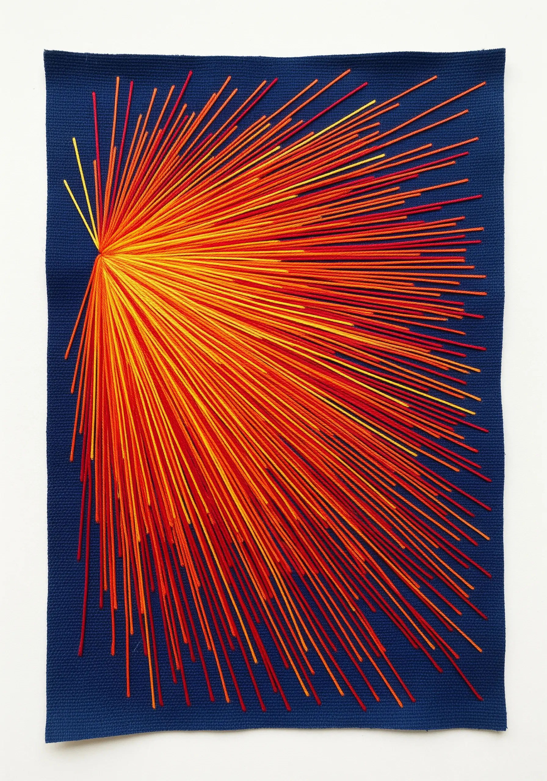 An explosive burst of radiating straight stitches in a red-to-yellow gradient on blue fabric.