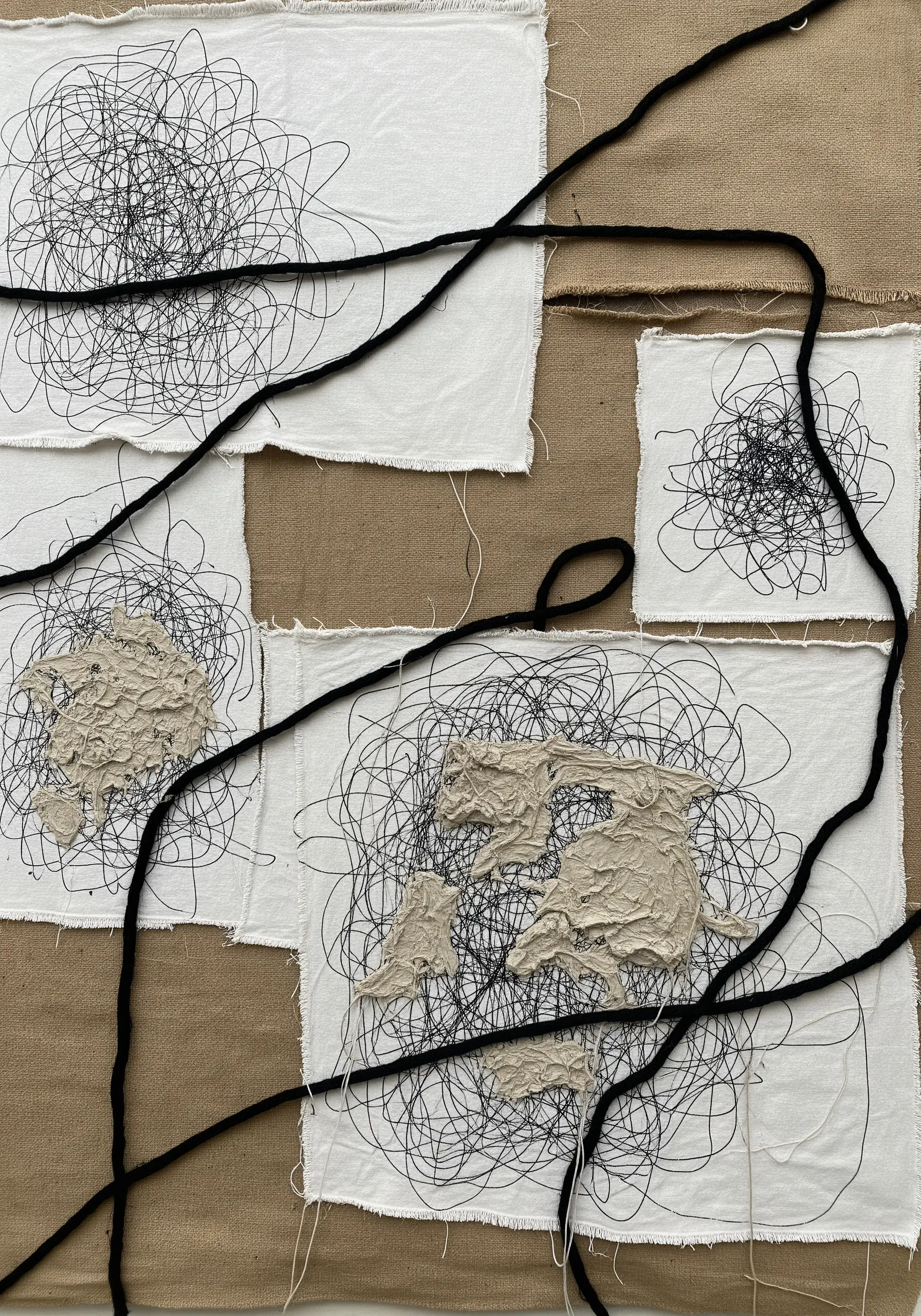 Abstract collage with free-motion machine stitching scribbles and thick black yarn.