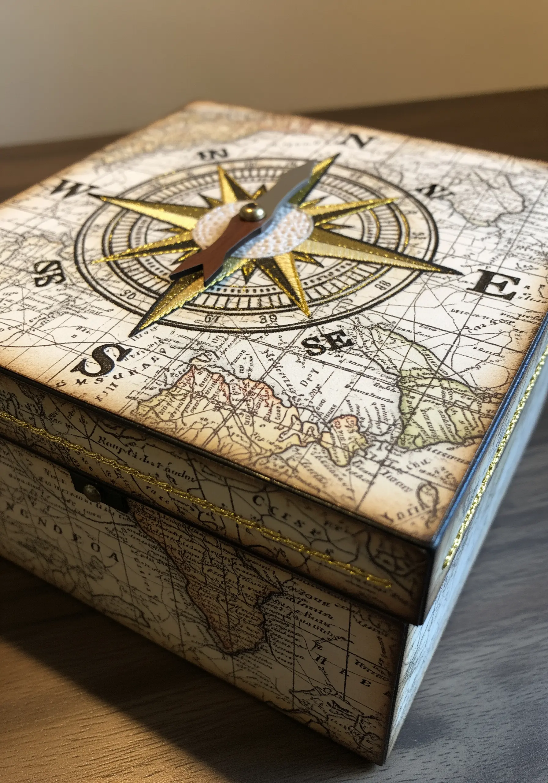 A vintage-style decoupage map box with an embroidered compass rose at its center.