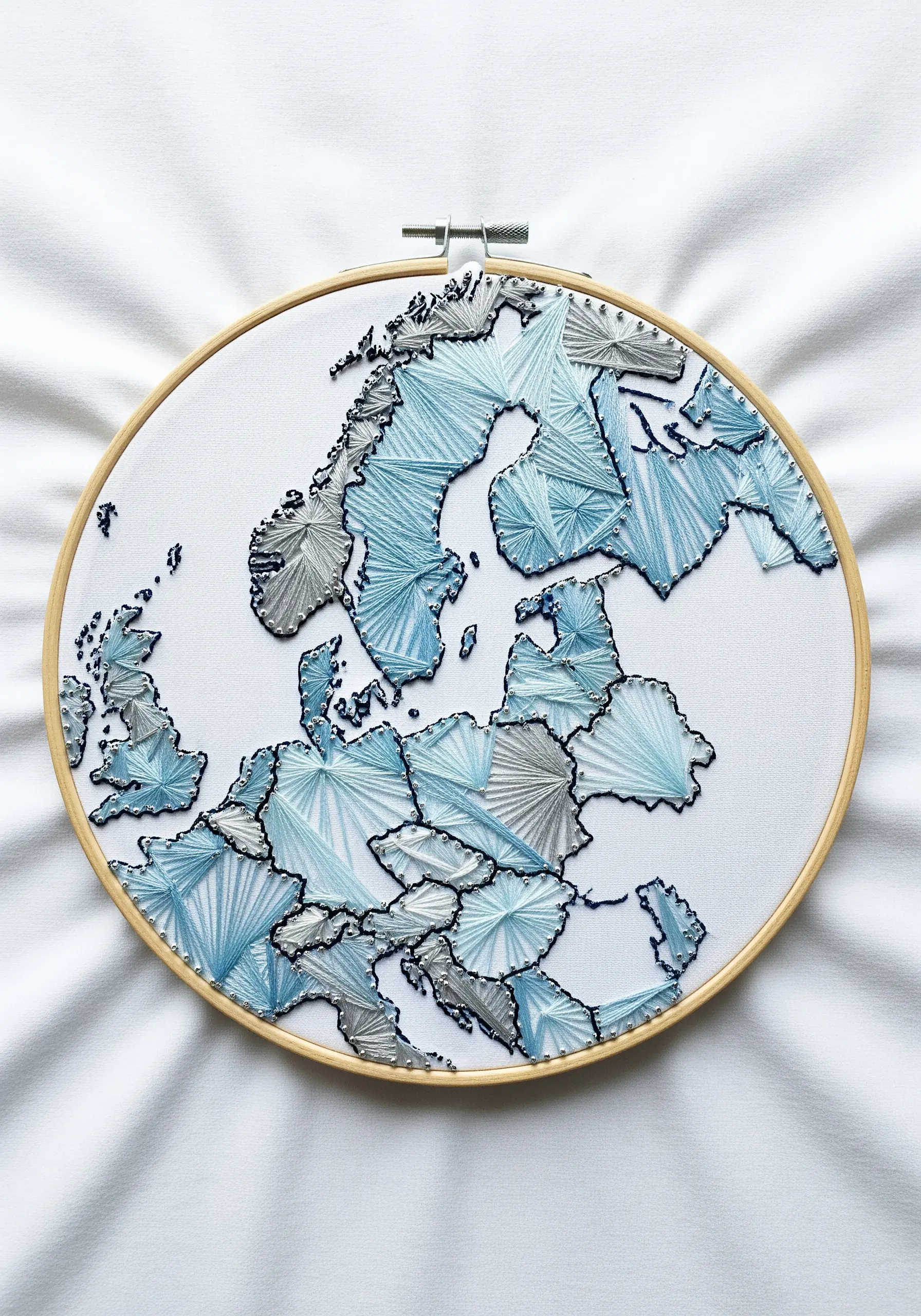 Hoop art map of Europe with each country filled with geometric patterns in blue and gray thread.