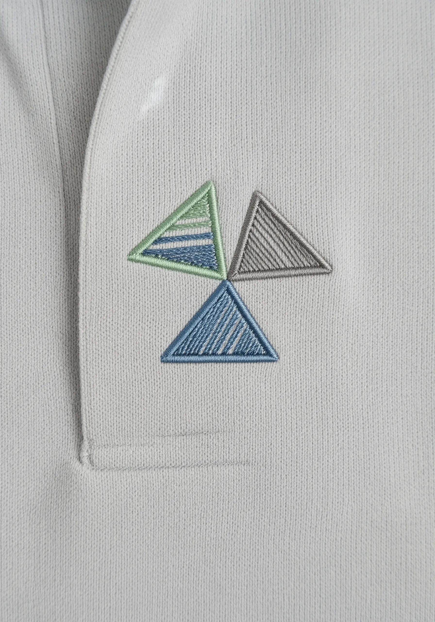 Three geometric triangles with parallel fill stitches on a gray polo shirt collar.