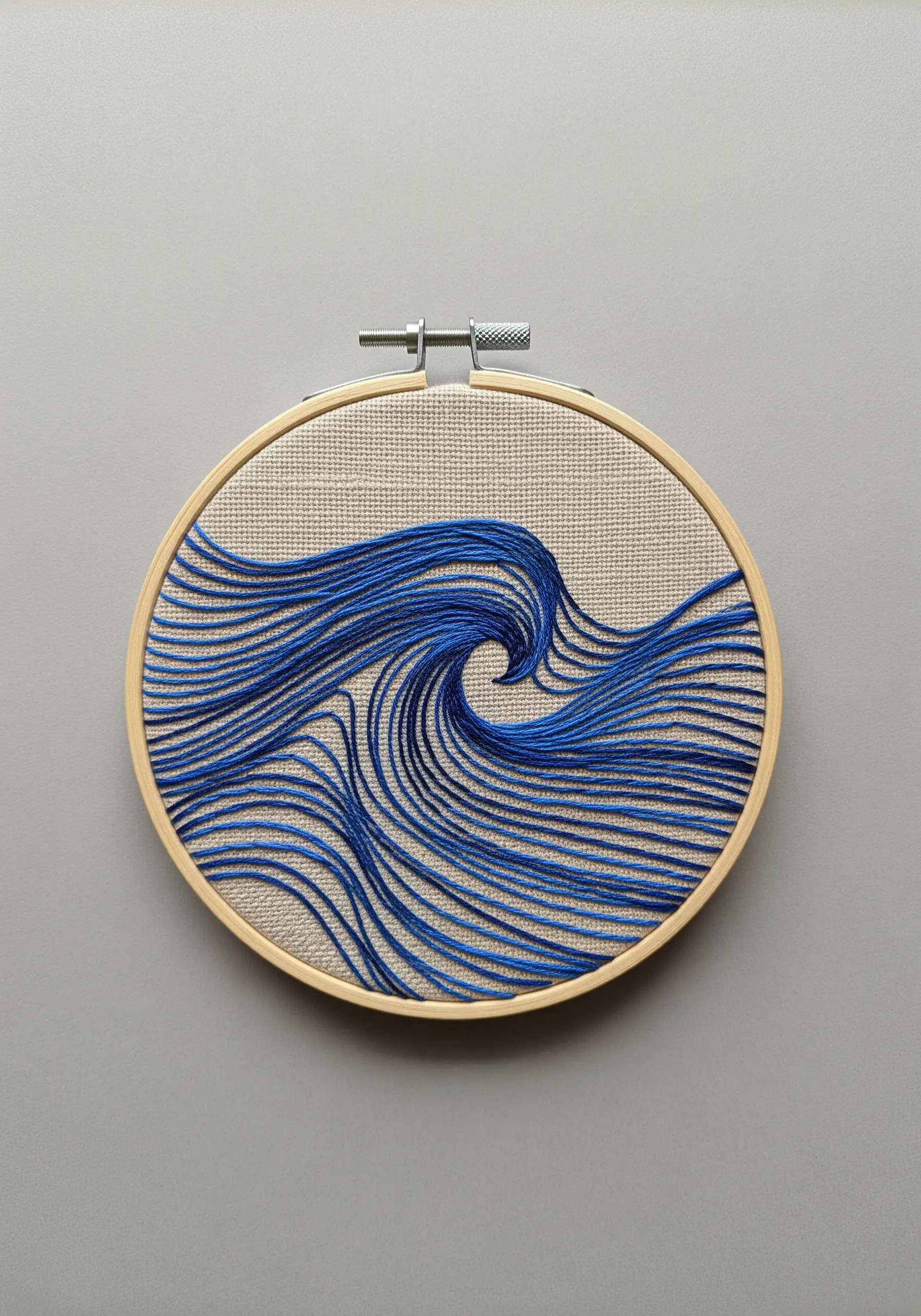 Abstract ocean wave created with flowing parallel lines of blue thread.