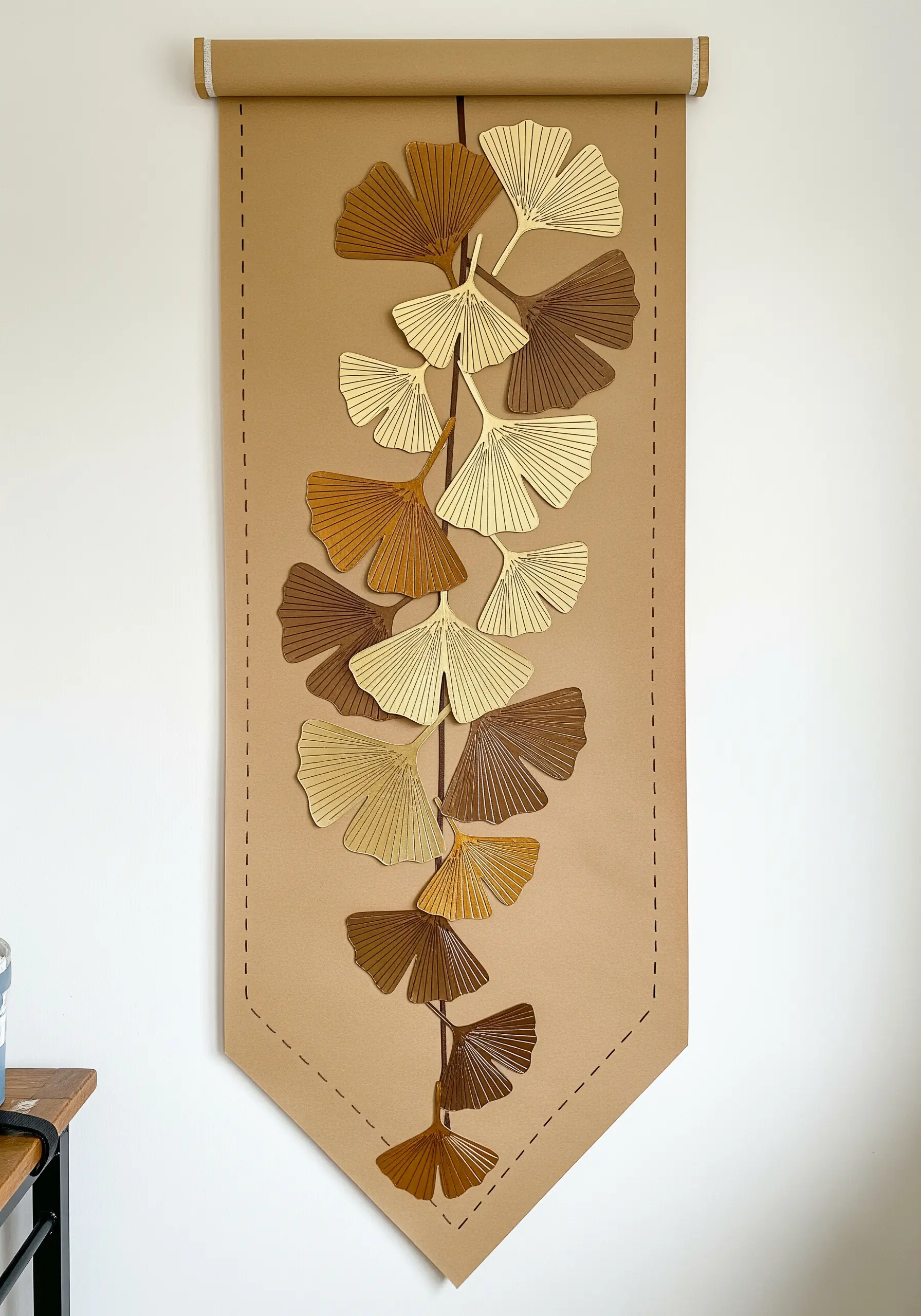 A long wall hanging made of paper ginkgo leaves stitched together down the center.