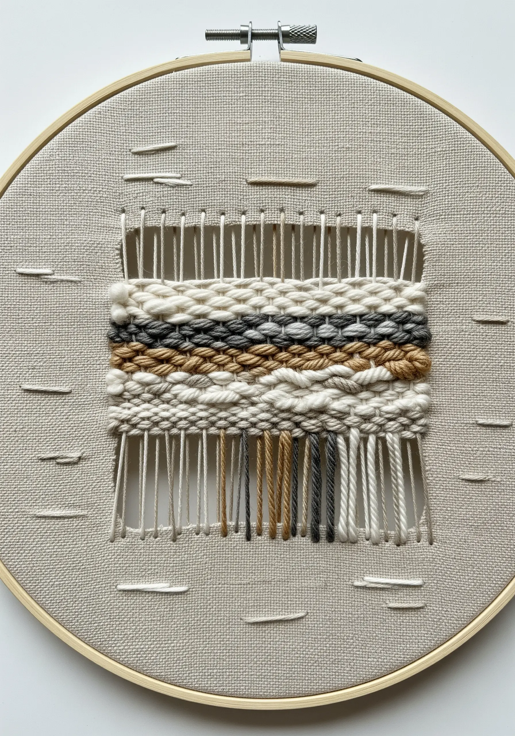 A small woven rectangle in a hoop with exposed warp threads at the top and bottom.