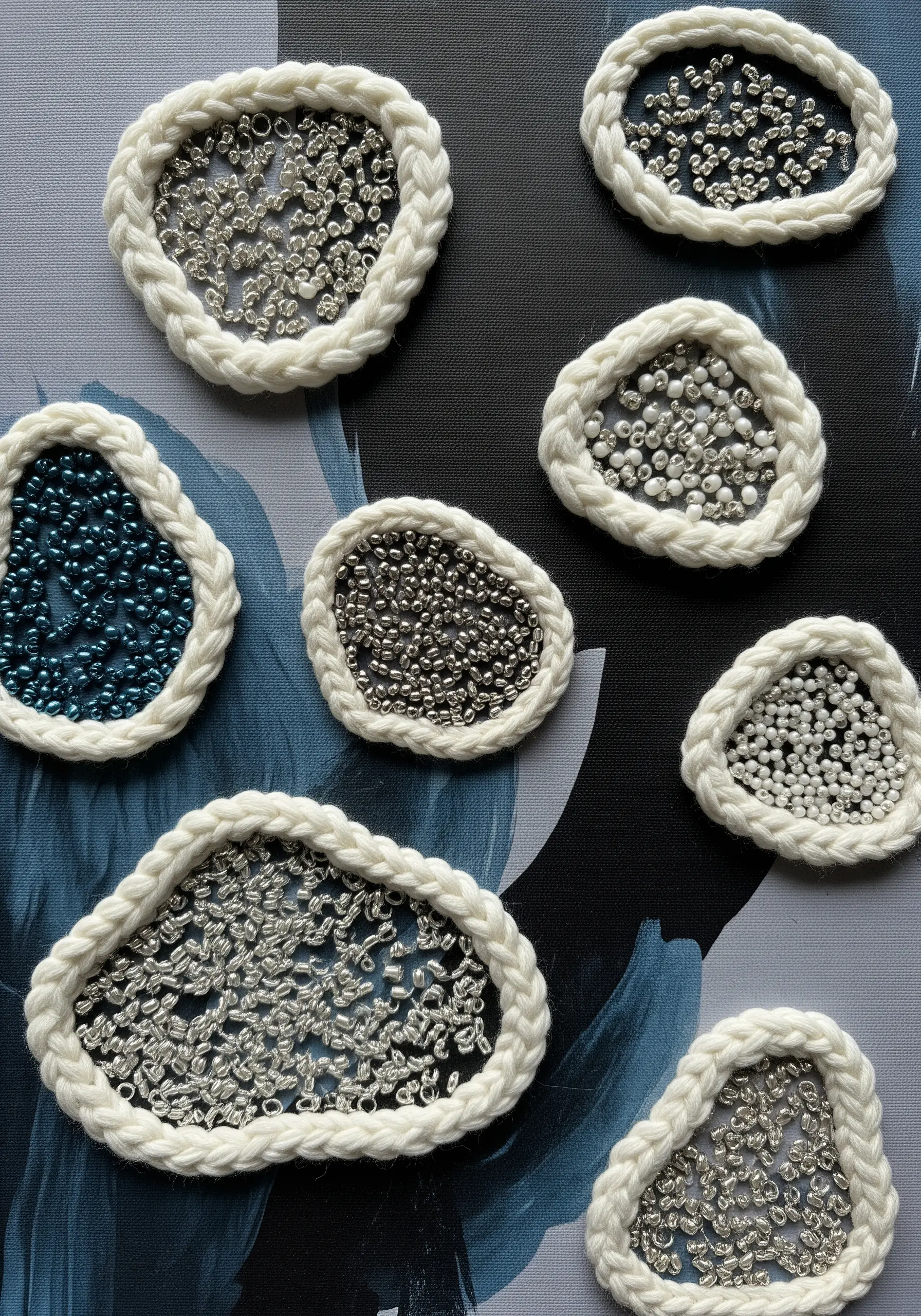 Abstract beaded forms outlined with white braided cord on a painted canvas.