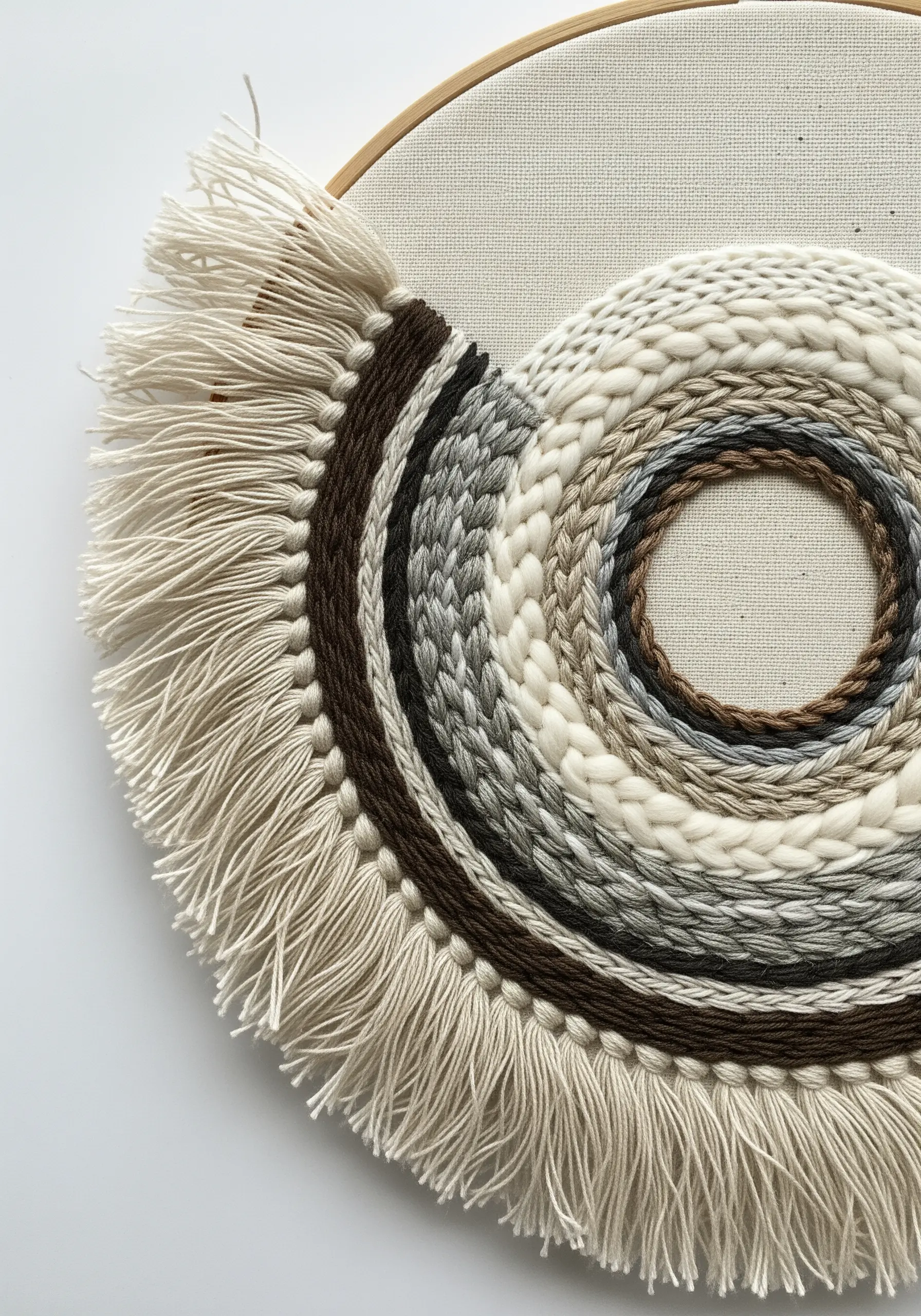 Circular weaving in a hoop with concentric rings and a neatly trimmed cream-colored fringe.