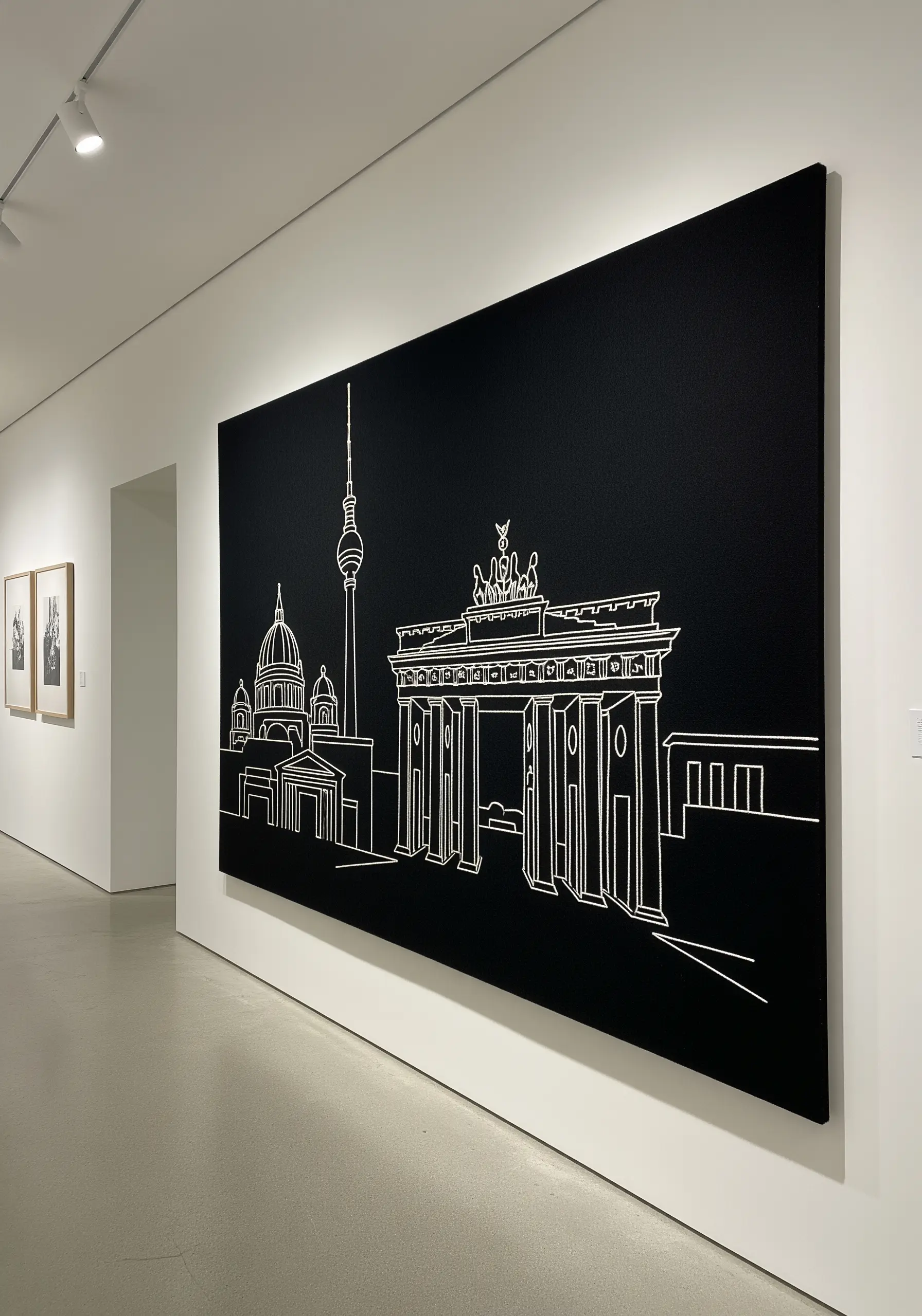 Large-scale minimalist line art embroidery of Berlin's Brandenburg Gate on black canvas.