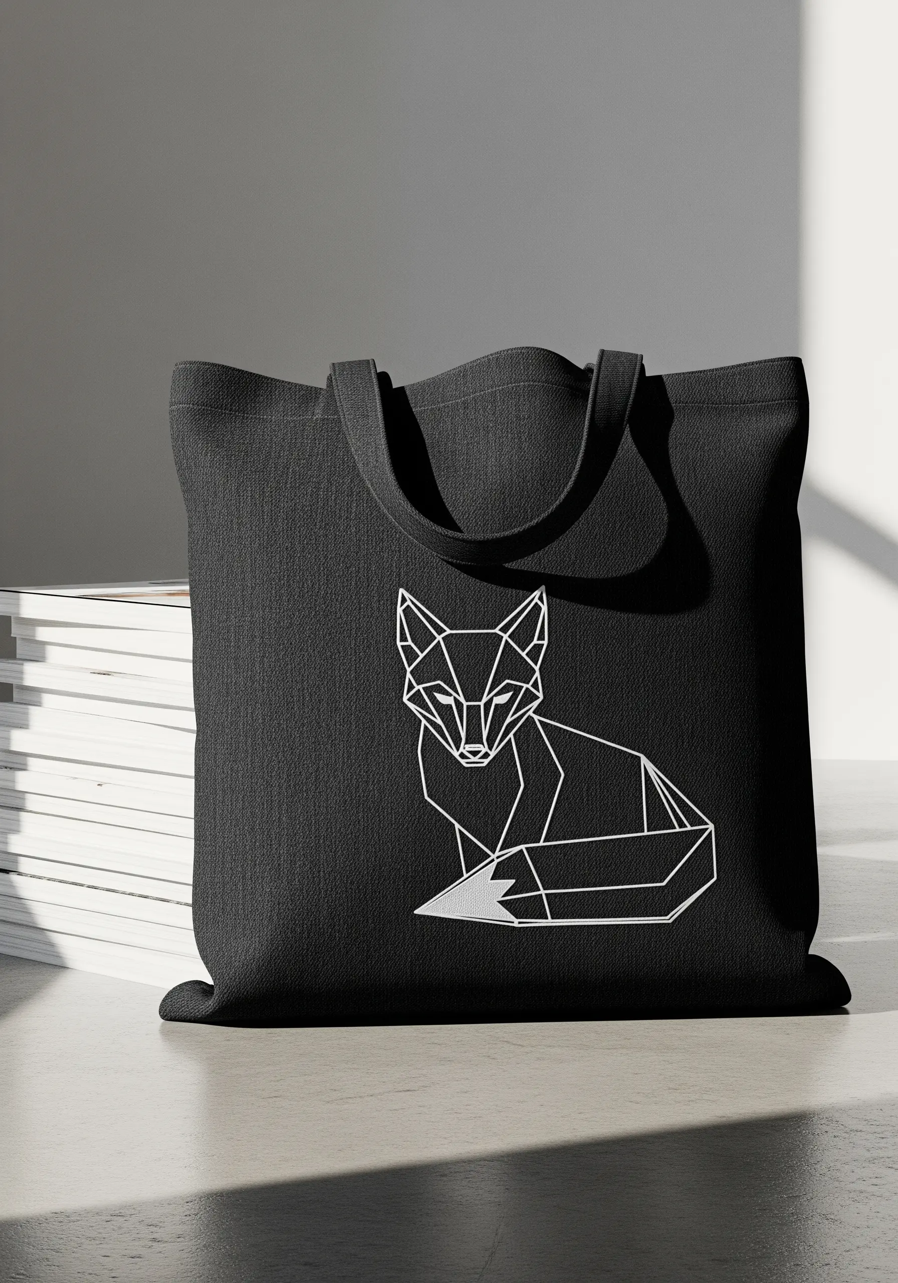 Geometric fox embroidered in white thread on a black canvas tote.