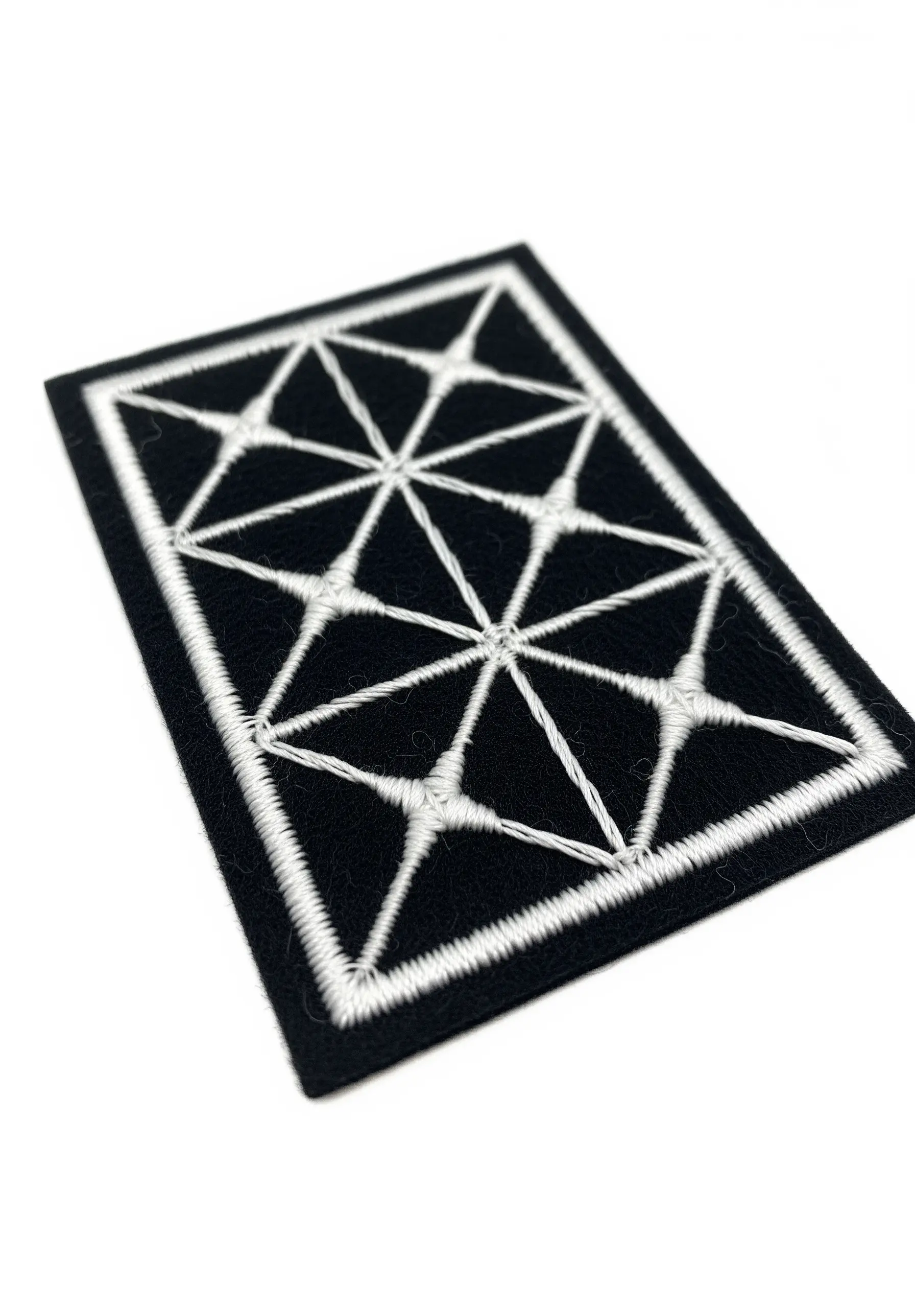 A geometric pattern in white thread on a black felt rectangular patch.