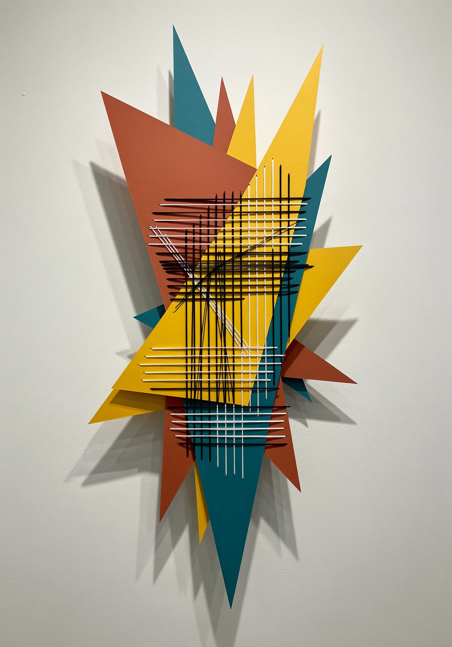 Abstract geometric paper collage with straight lines of black and white thread creating a grid.