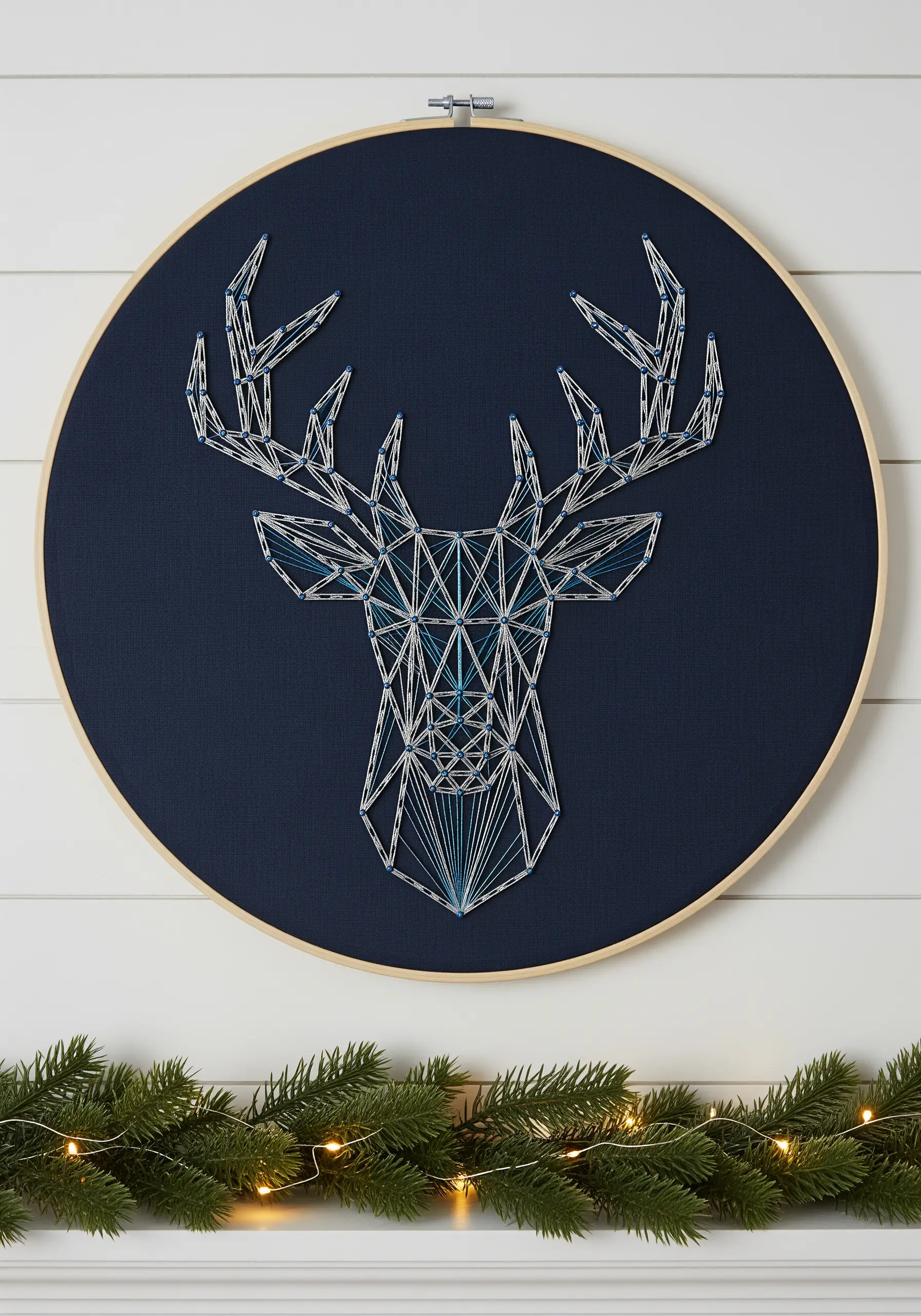 Geometric deer head string art with layered blue and white thread on dark fabric.