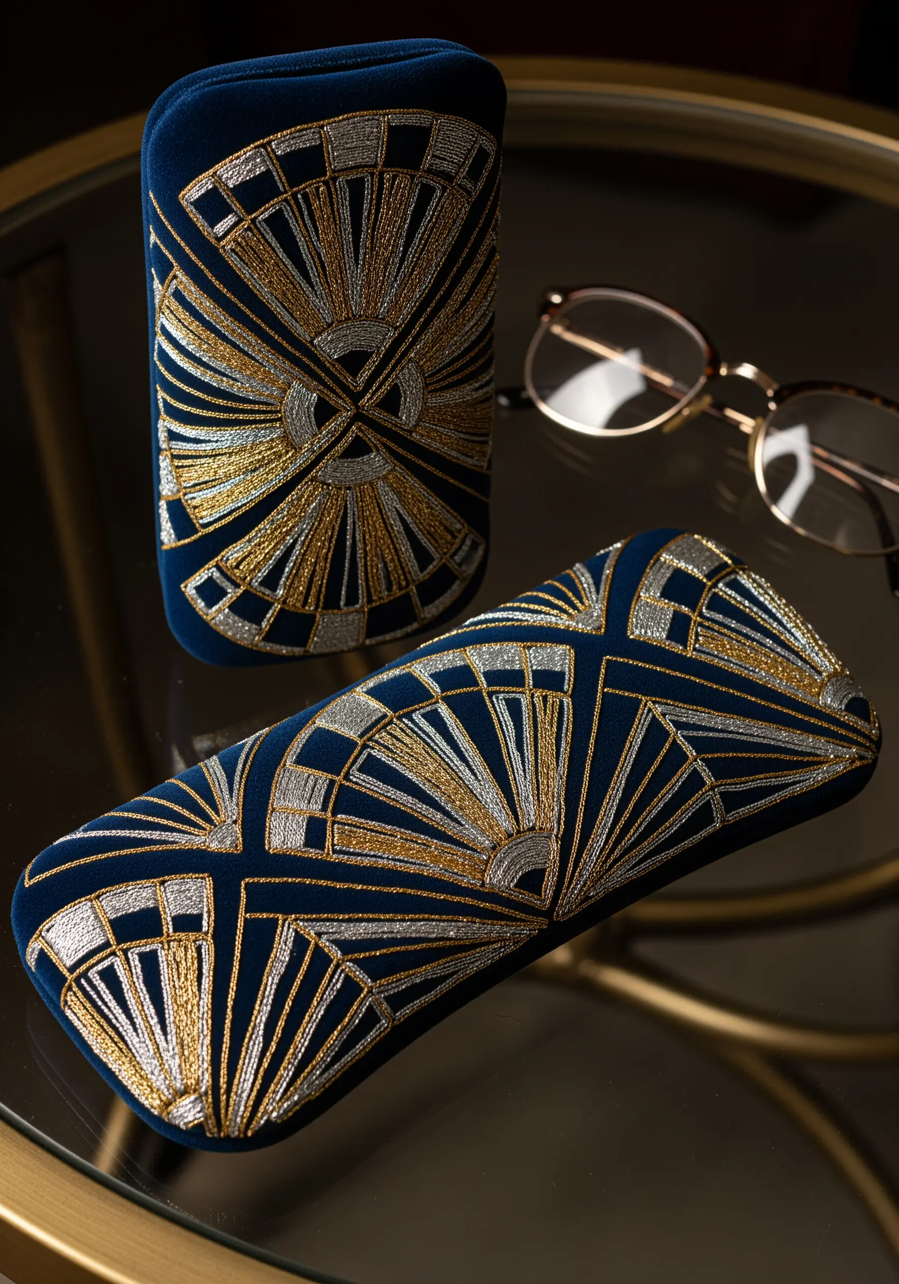 Two velvet eyeglass cases with symmetrical Art Deco fan patterns in gold and silver metallic thread.