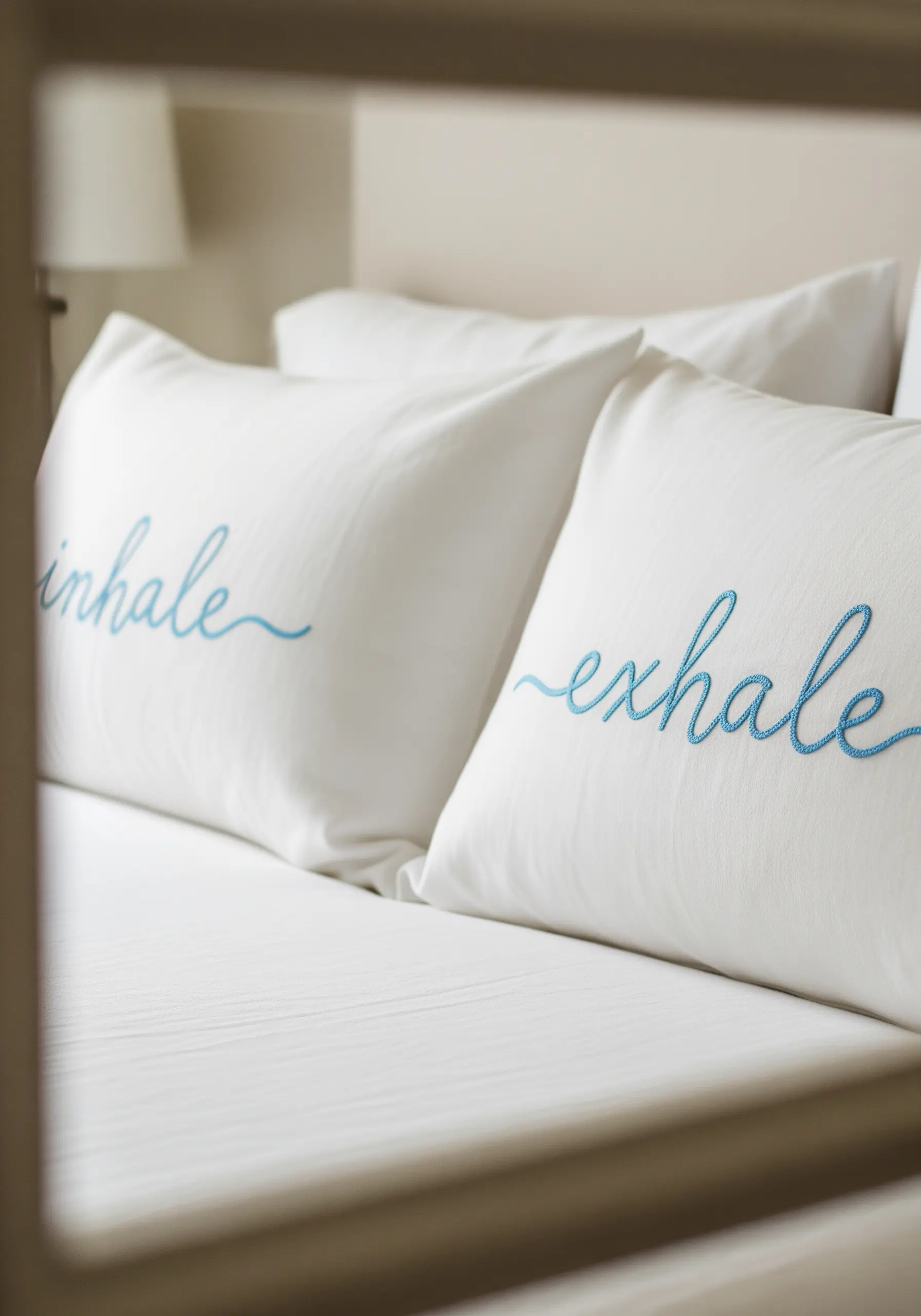 Two white pillows with the words 'inhale' and 'exhale' embroidered in blue script.