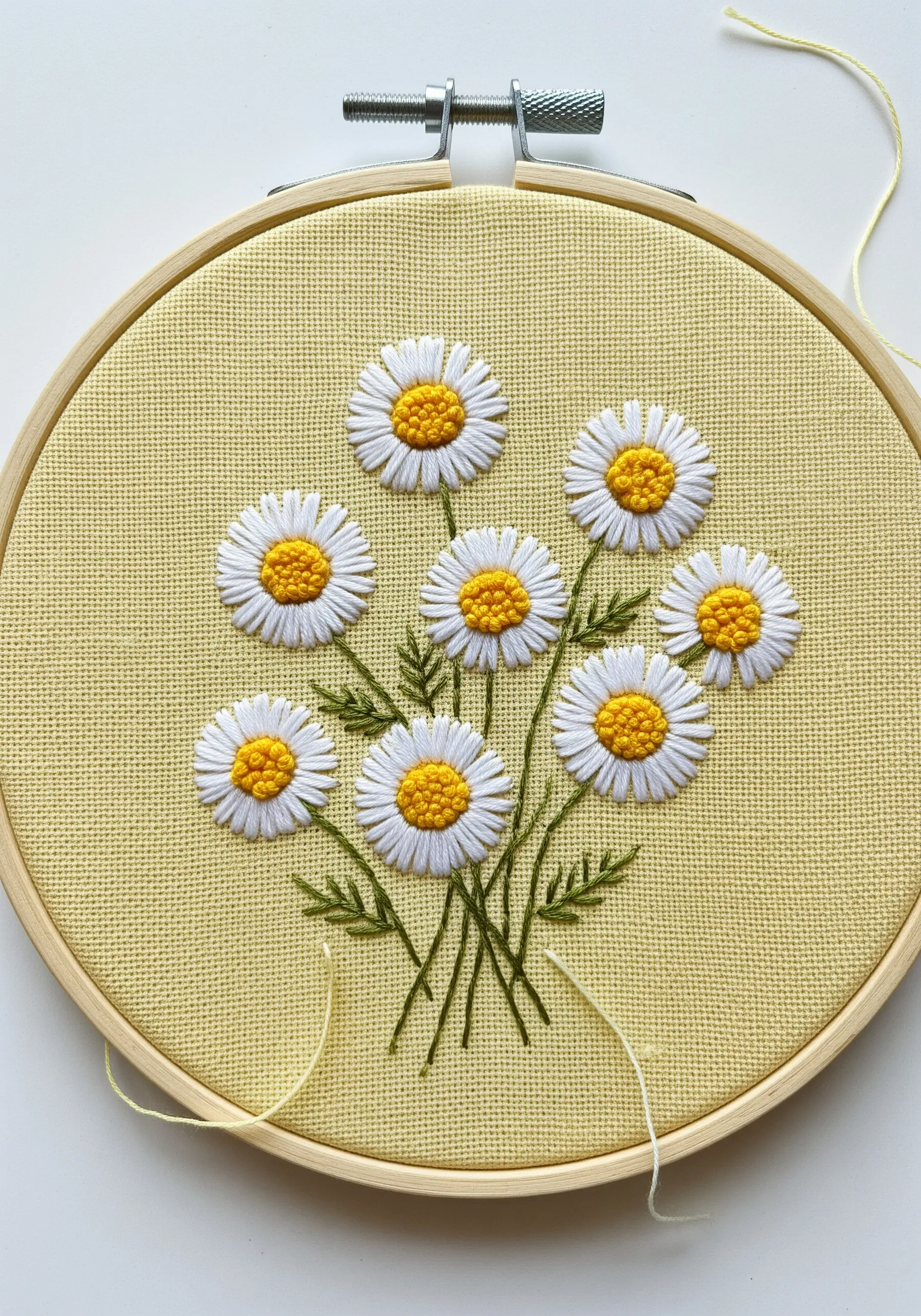A bouquet of embroidered daisies with textured yellow woven-wheel centers on yellow fabric.