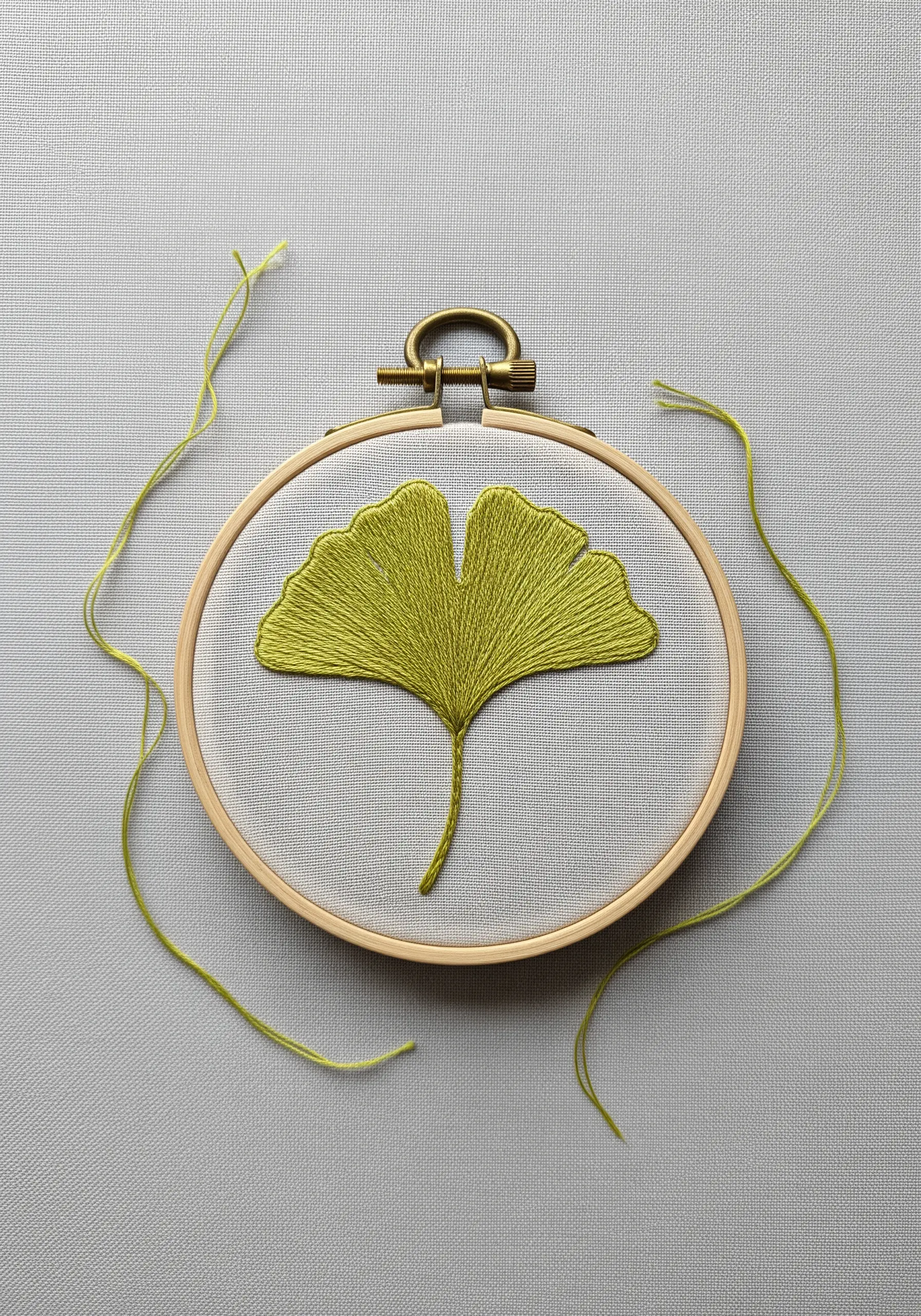 A green ginkgo leaf filled with directional satin stitches that fan outwards.