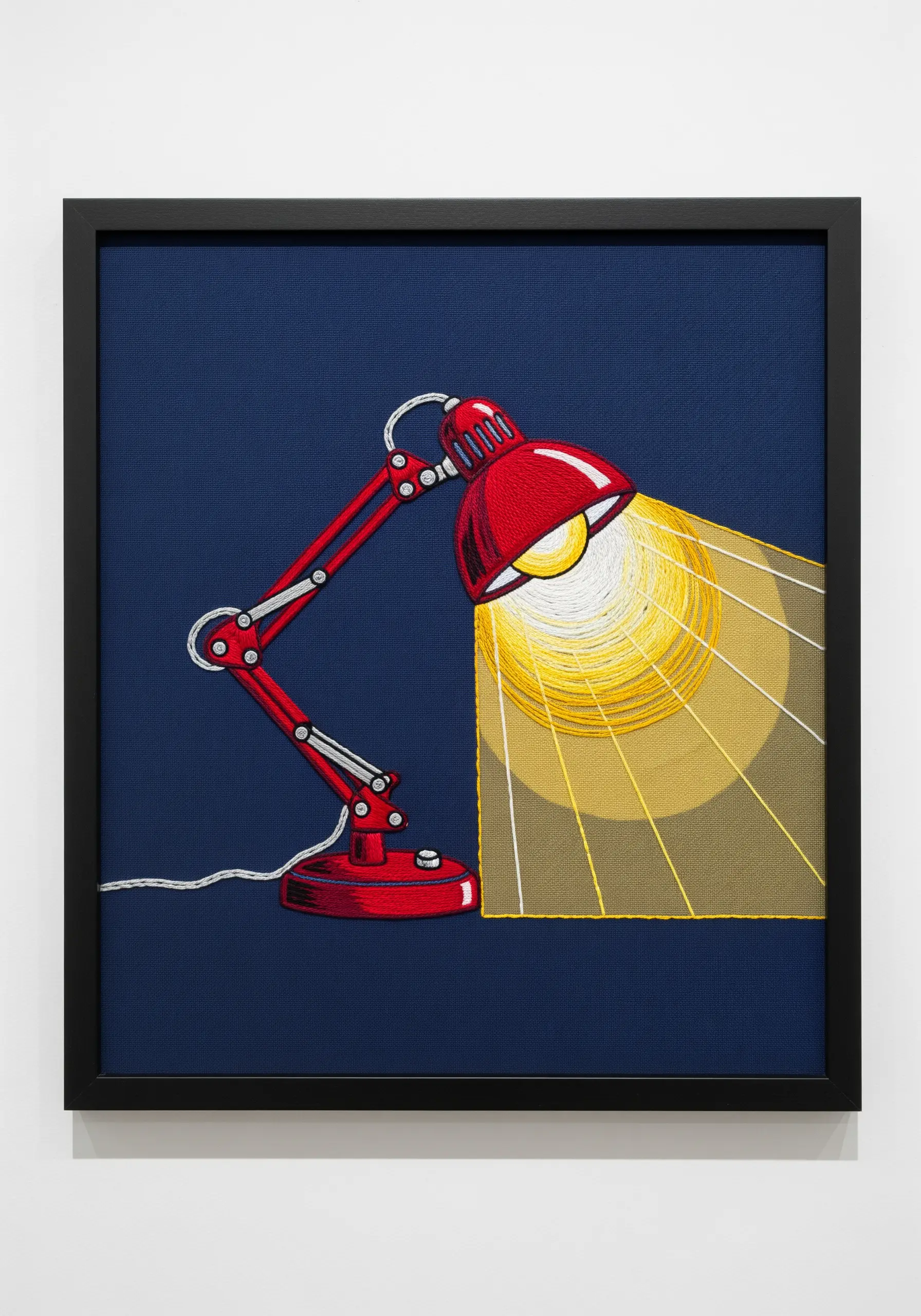 An embroidered red desk lamp casting a beam of yellow and white light.