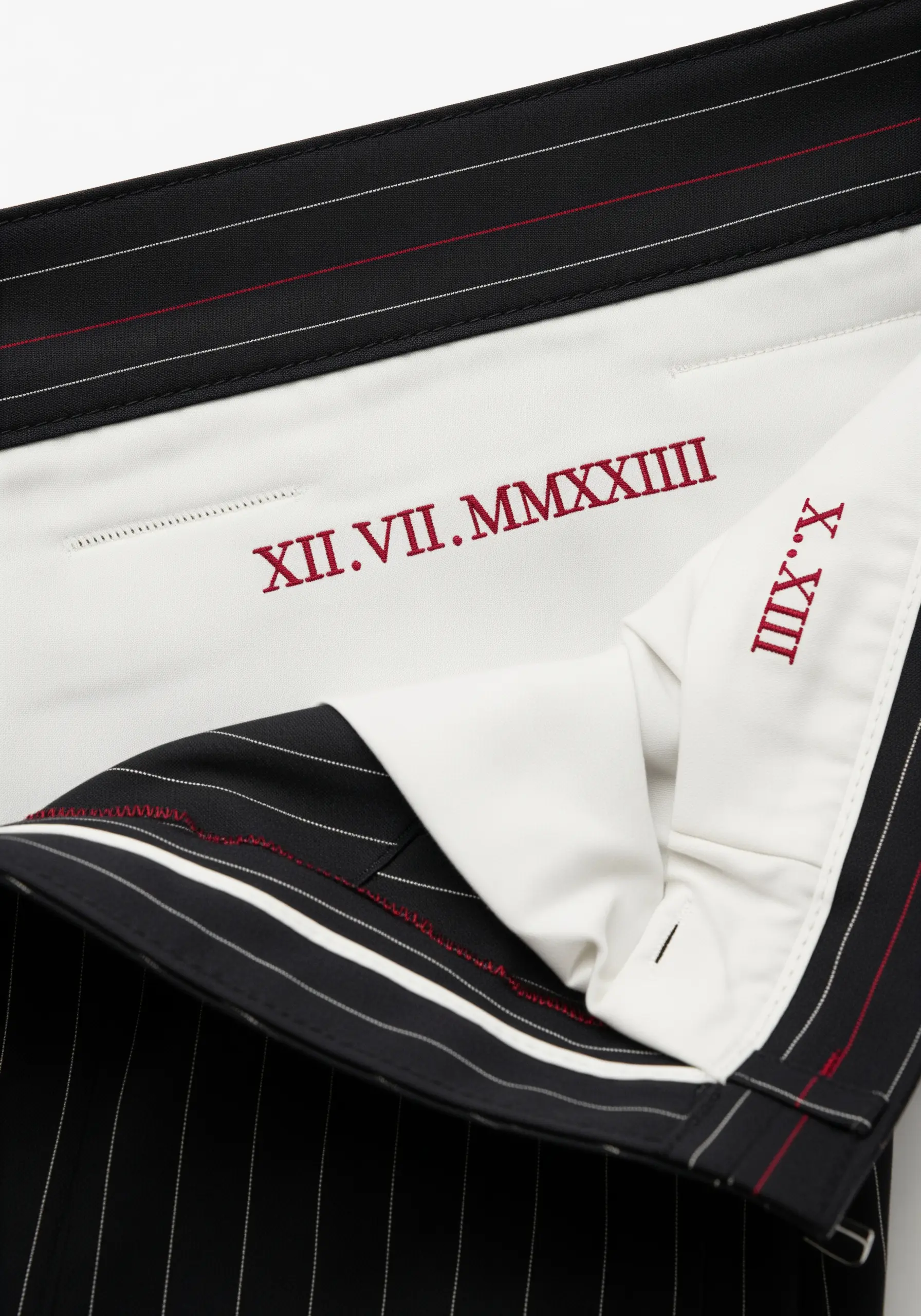 A date in Roman numerals embroidered in red thread on the white inner waistband of pinstripe trousers.