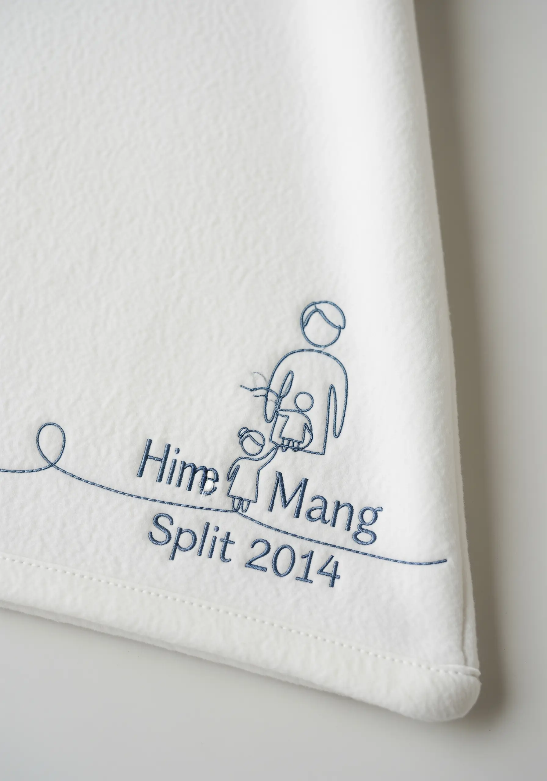 Line art motif with custom text on a fleece blanket, stitched in a single color.