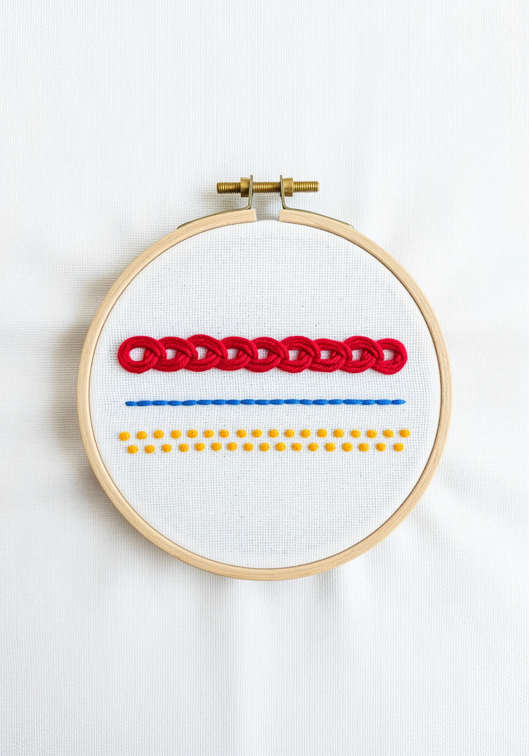 A stitch sampler with three distinct lines of stitches in red, blue, and yellow.
