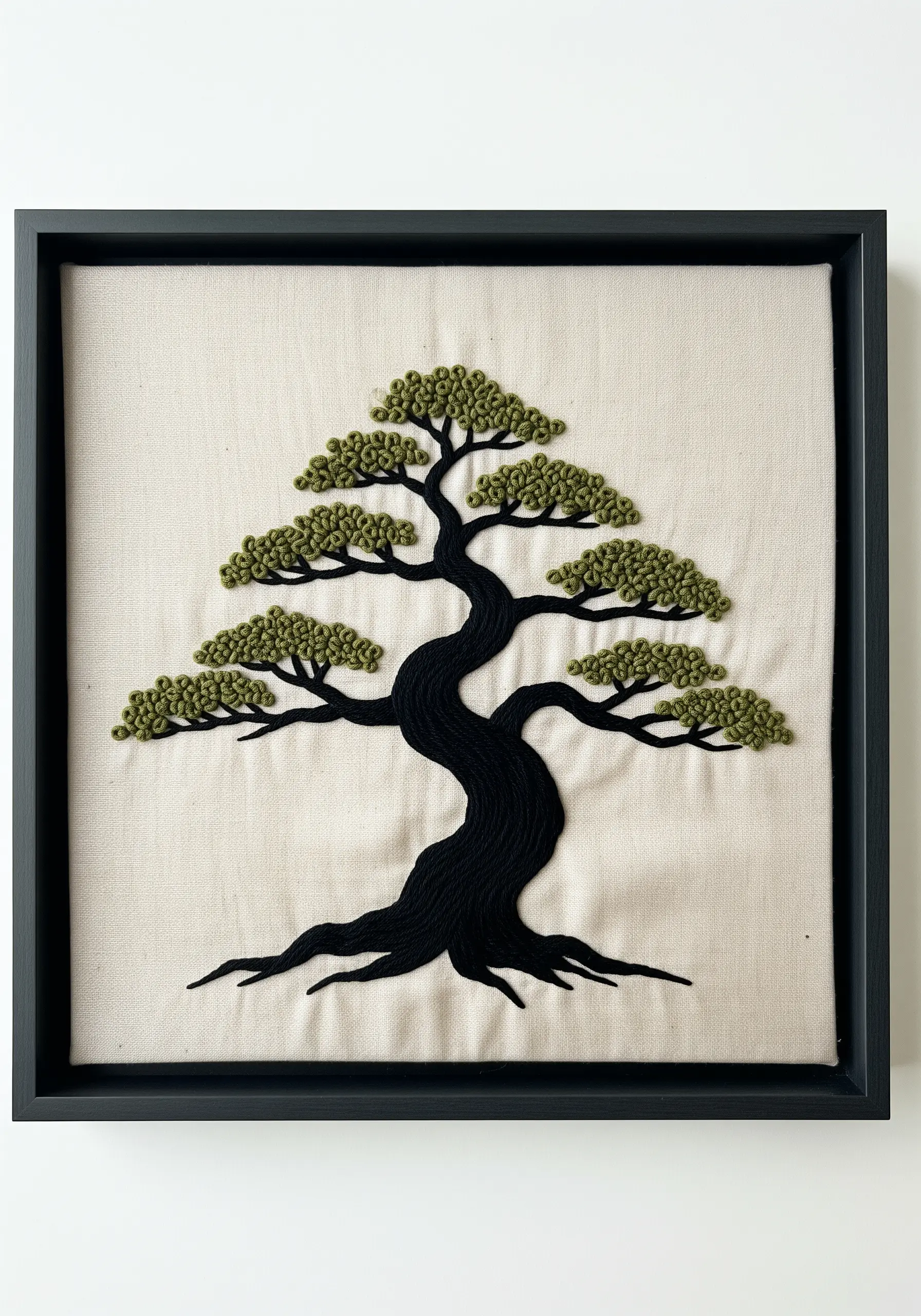 A bonsai tree with a smooth black satin-stitched trunk and dense green French knot foliage.
