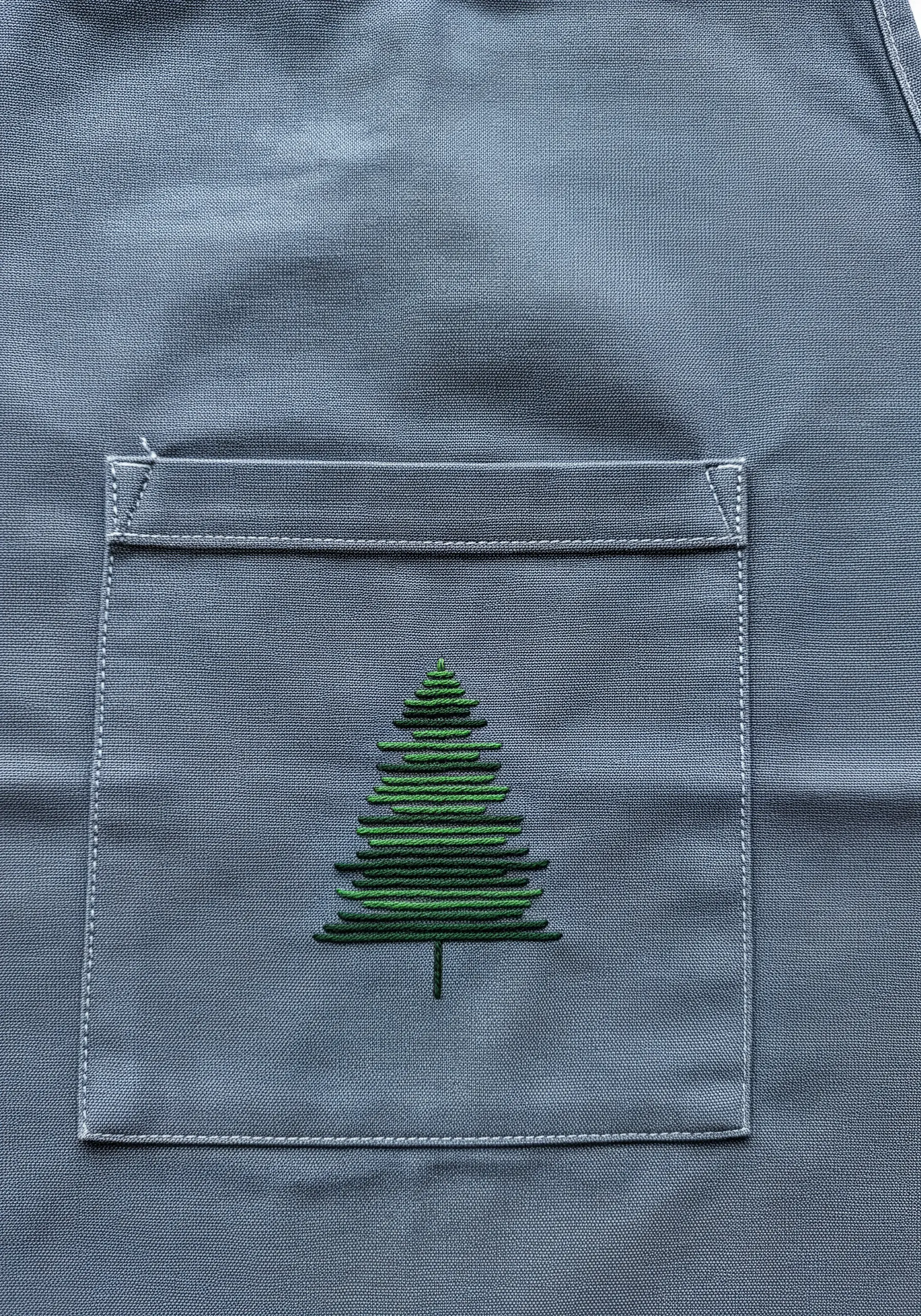 A modern, graphic Christmas tree made of stacked satin stitches on an apron pocket.