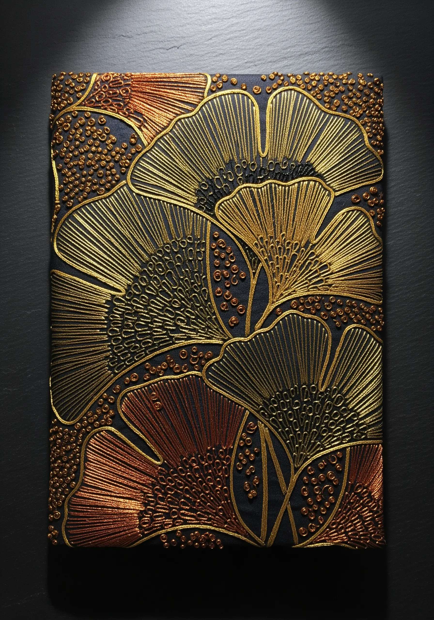 Overlapping Ginkgo leaves embroidered in gold, bronze, and black metallic threads on dark canvas.