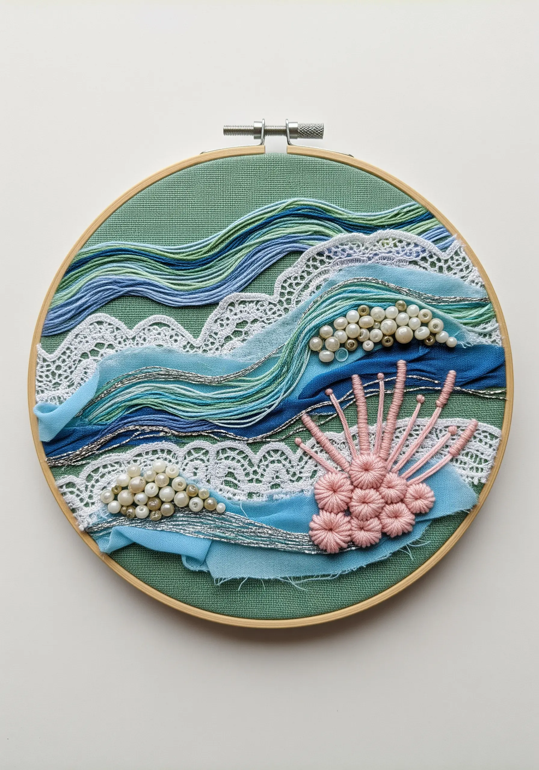 Abstract seascape embroidery with layered lace, sheer blue fabric, pearls, and textural stitches.