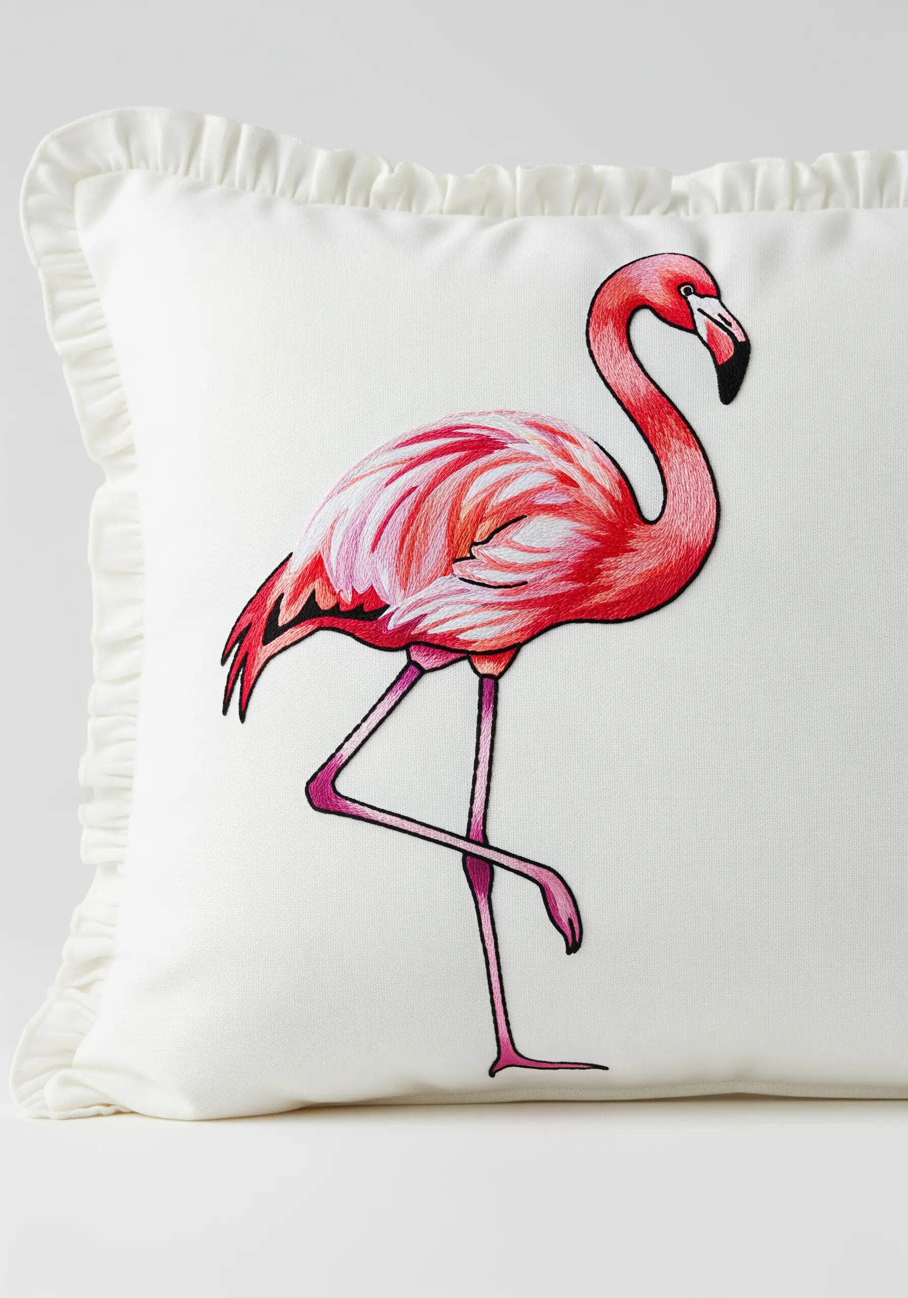 Embroidered flamingo on a white pillow with layered pink and white stitching for feathers.