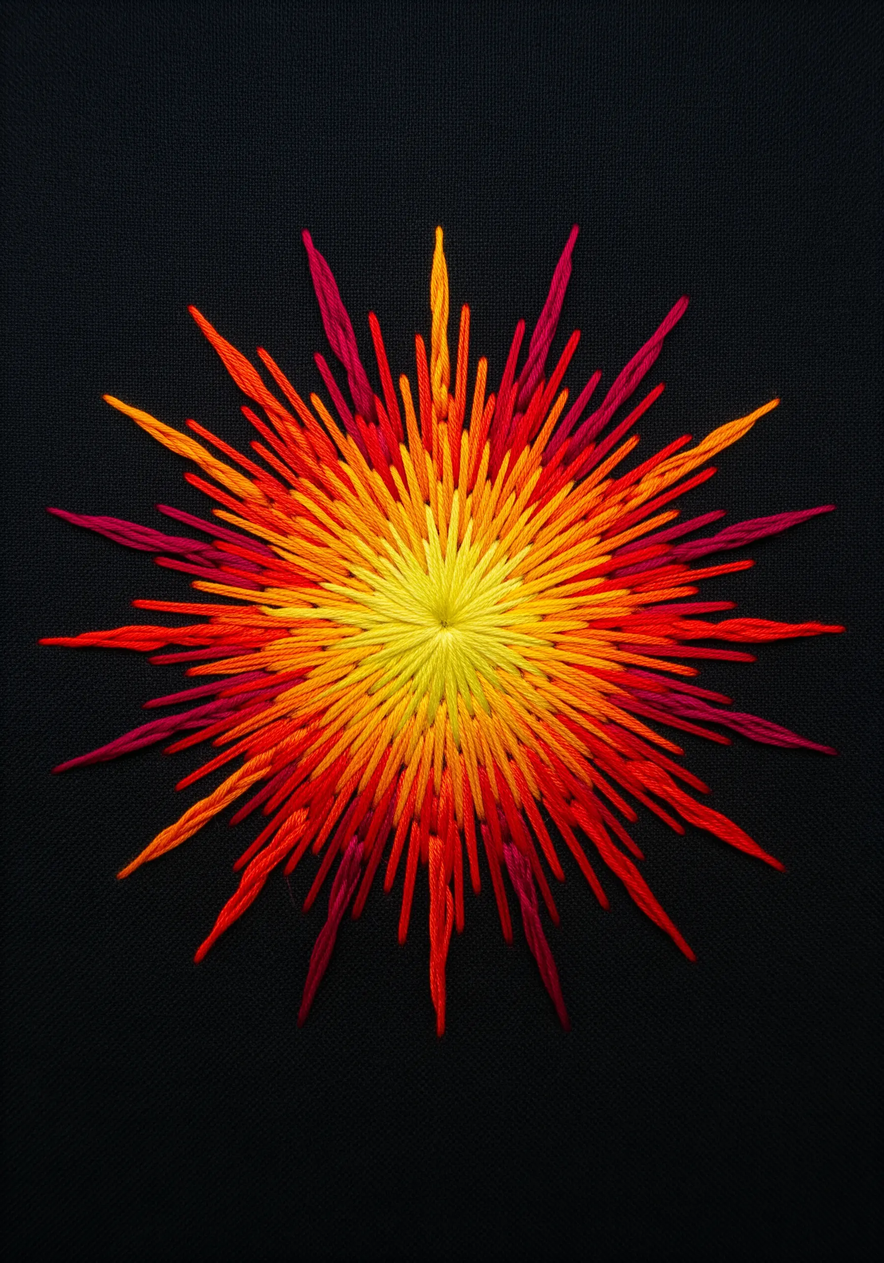 Fiery sunburst embroidery with layered straight stitches in red, orange, and yellow.