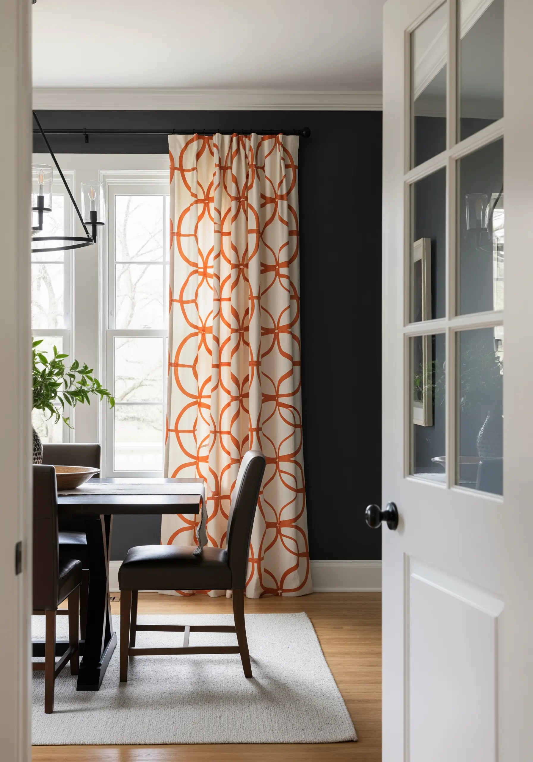 Large, interlocking orange circles embroidered on a cream curtain in a dark room.