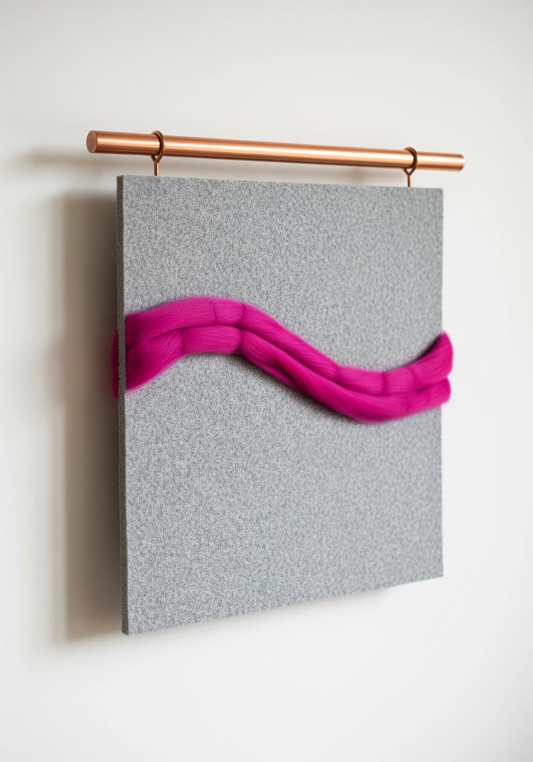 Minimalist wall art with a bold swipe of pink wool roving on a gray felt panel.