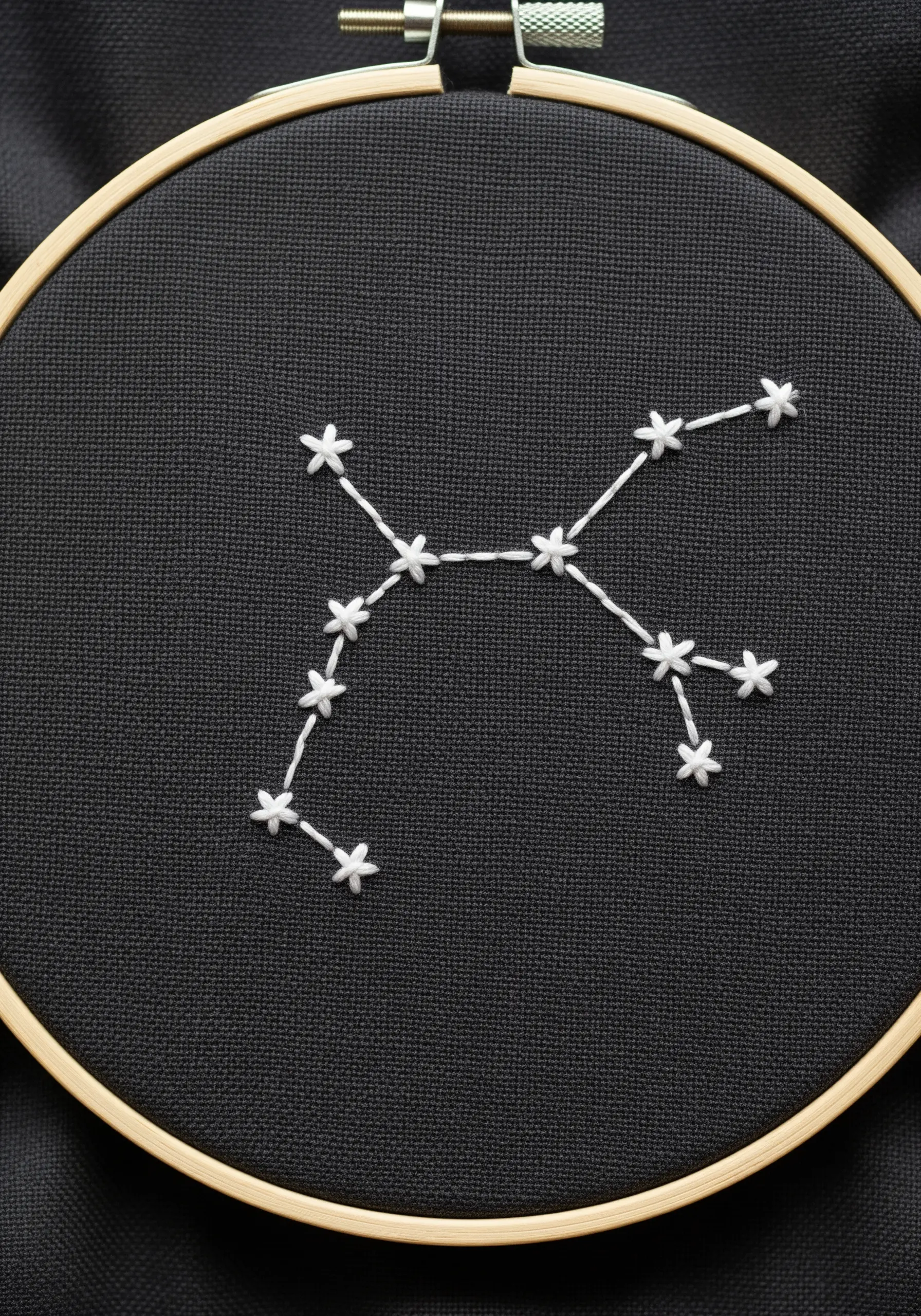 A white-thread constellation stitched on black fabric, with tiny star stitches.