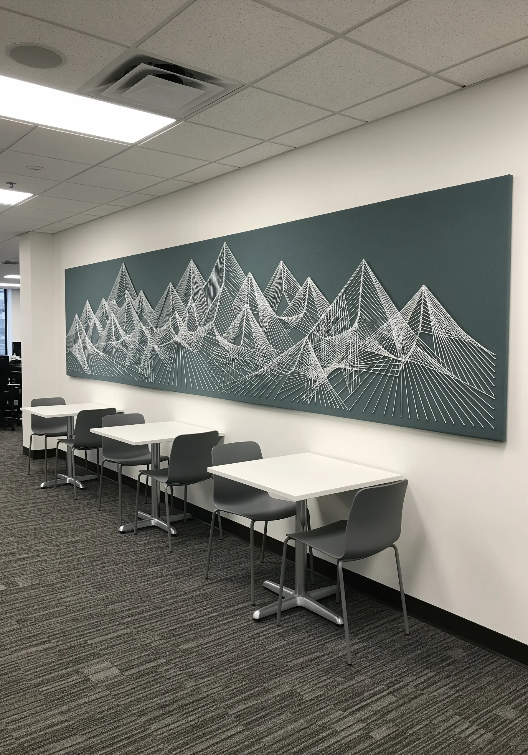 Large-scale string art of an abstract mountain range created with intersecting white lines on a dark wall.
