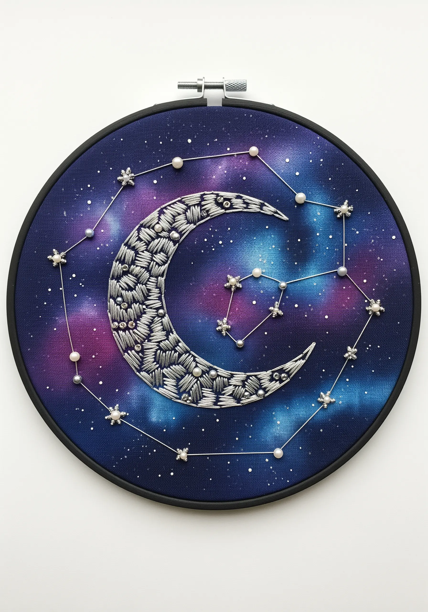 Embroidered crescent moon on a painted galaxy background with pearl bead constellations.