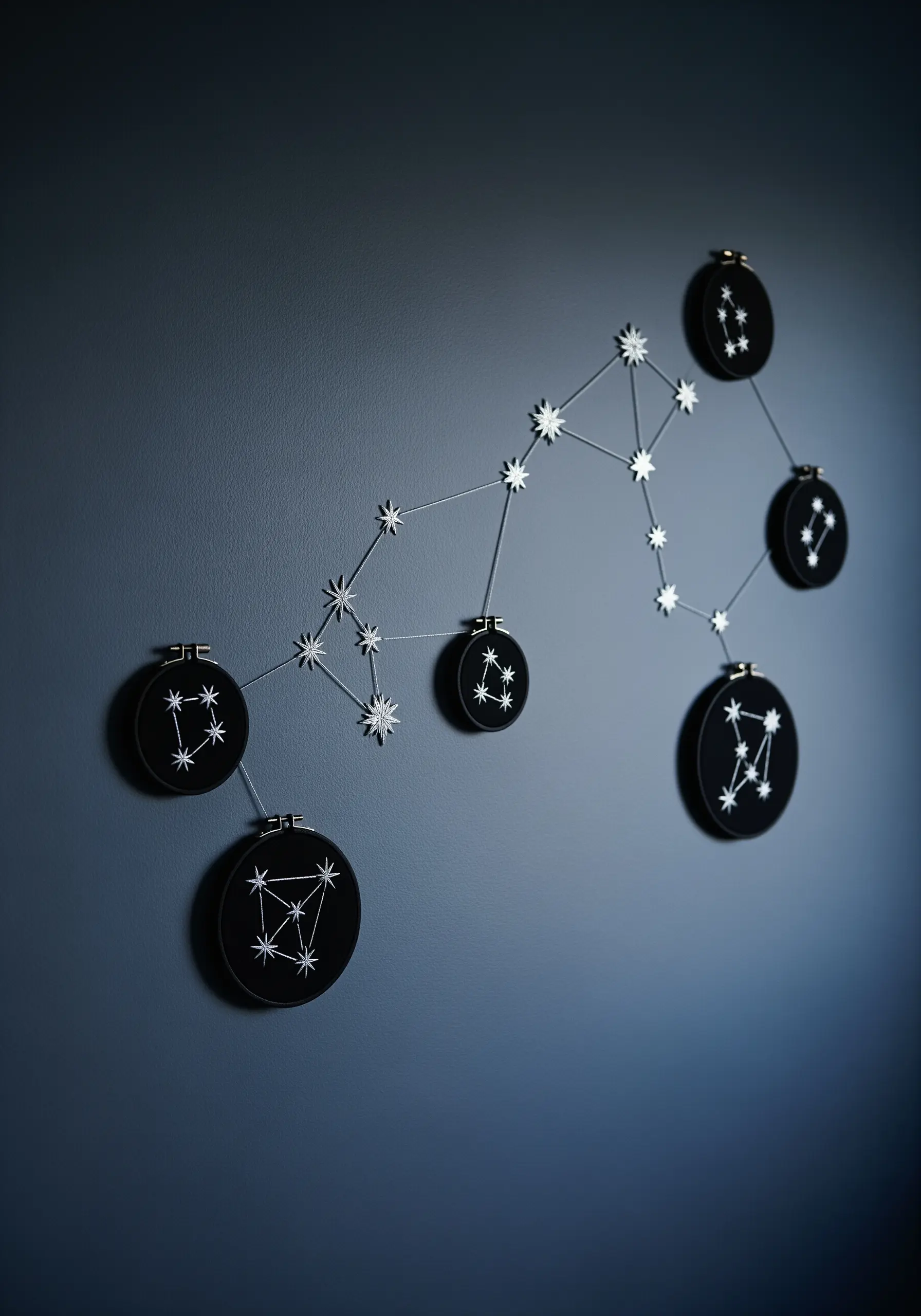 An embroidered constellation map created by connecting multiple black hoops on a dark wall.