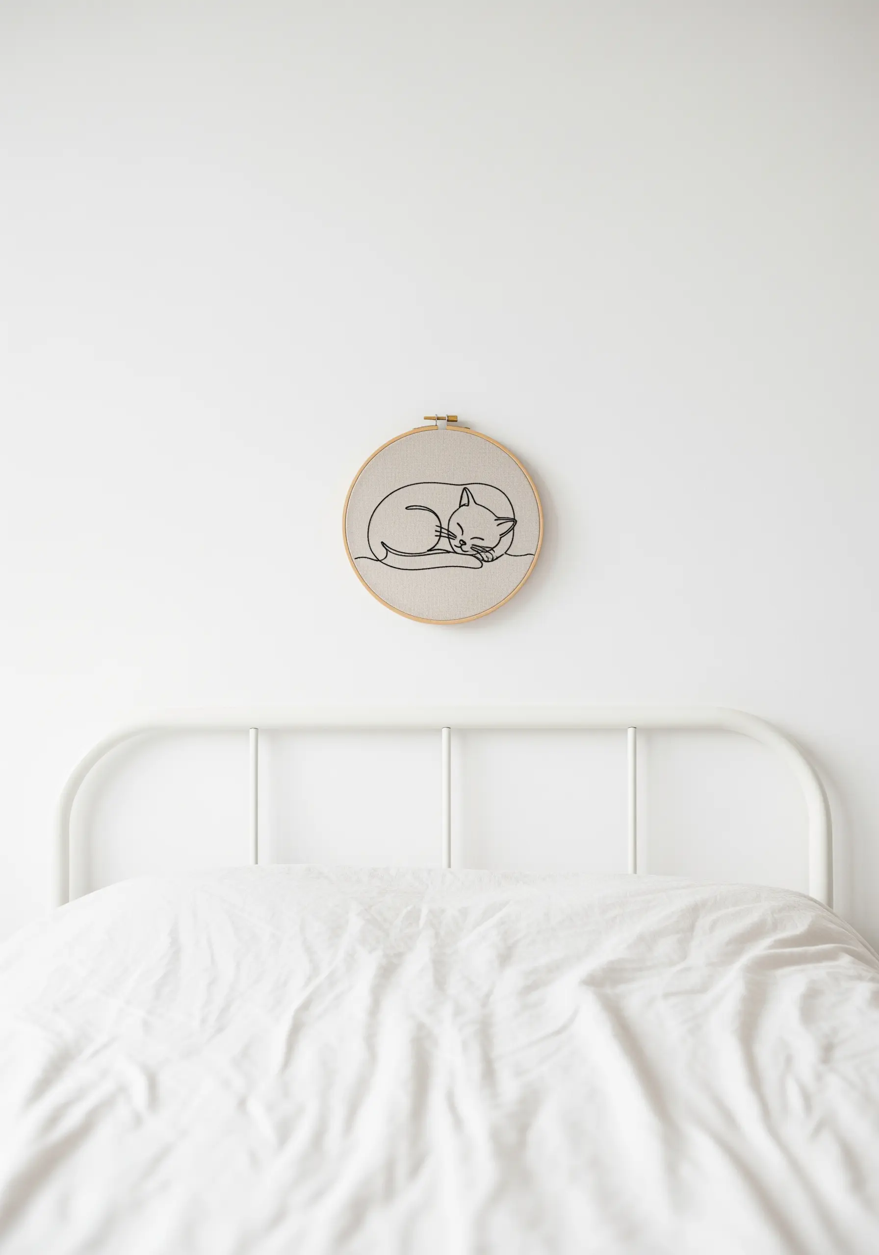 Minimalist line art embroidery of a sleeping cat in a small wooden hoop.