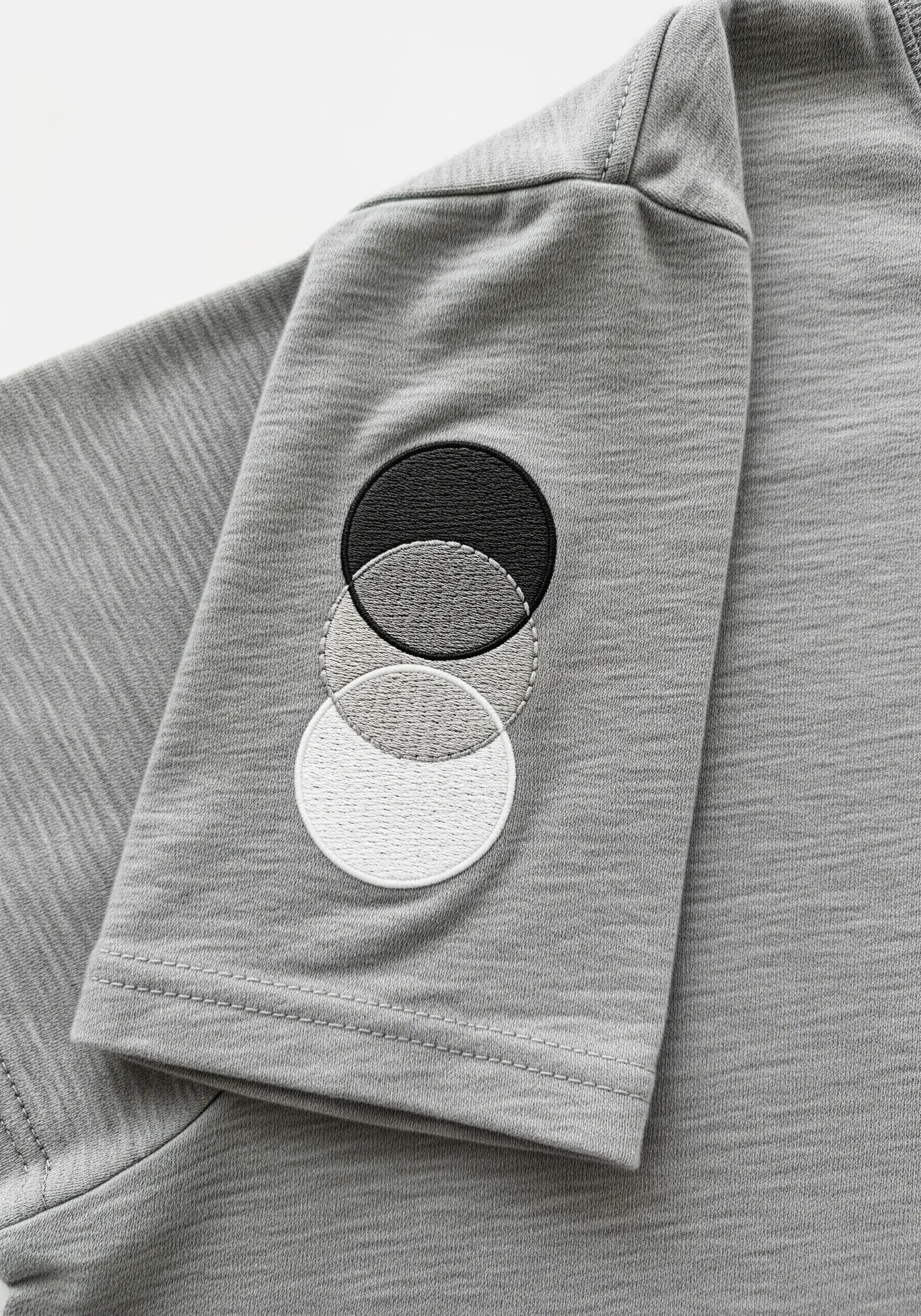 Three overlapping circles in black, gray, and white on a gray t-shirt sleeve.