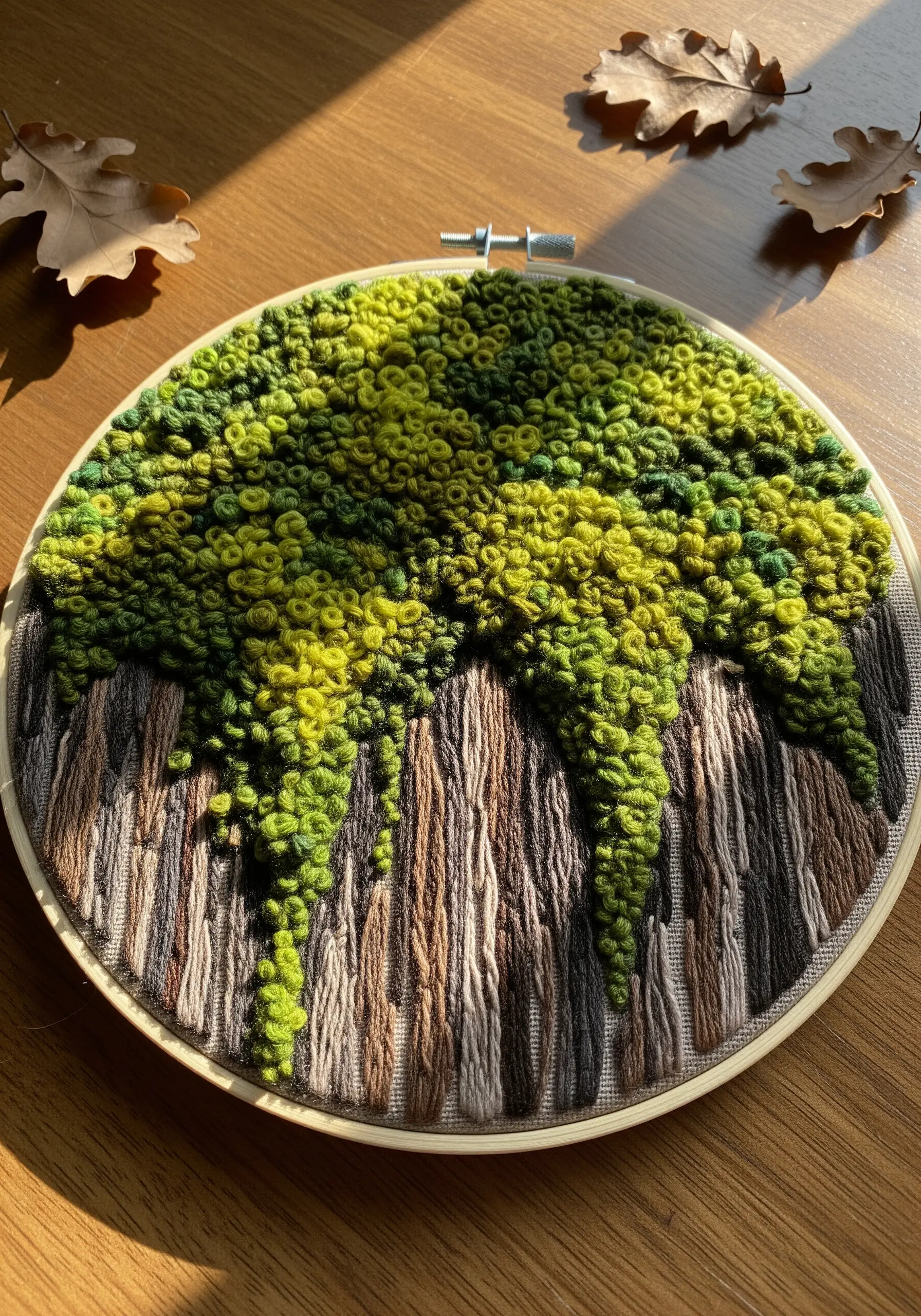 Embroidery hoop with dense green French knots and brown straight stitches creating a mossy bark texture.