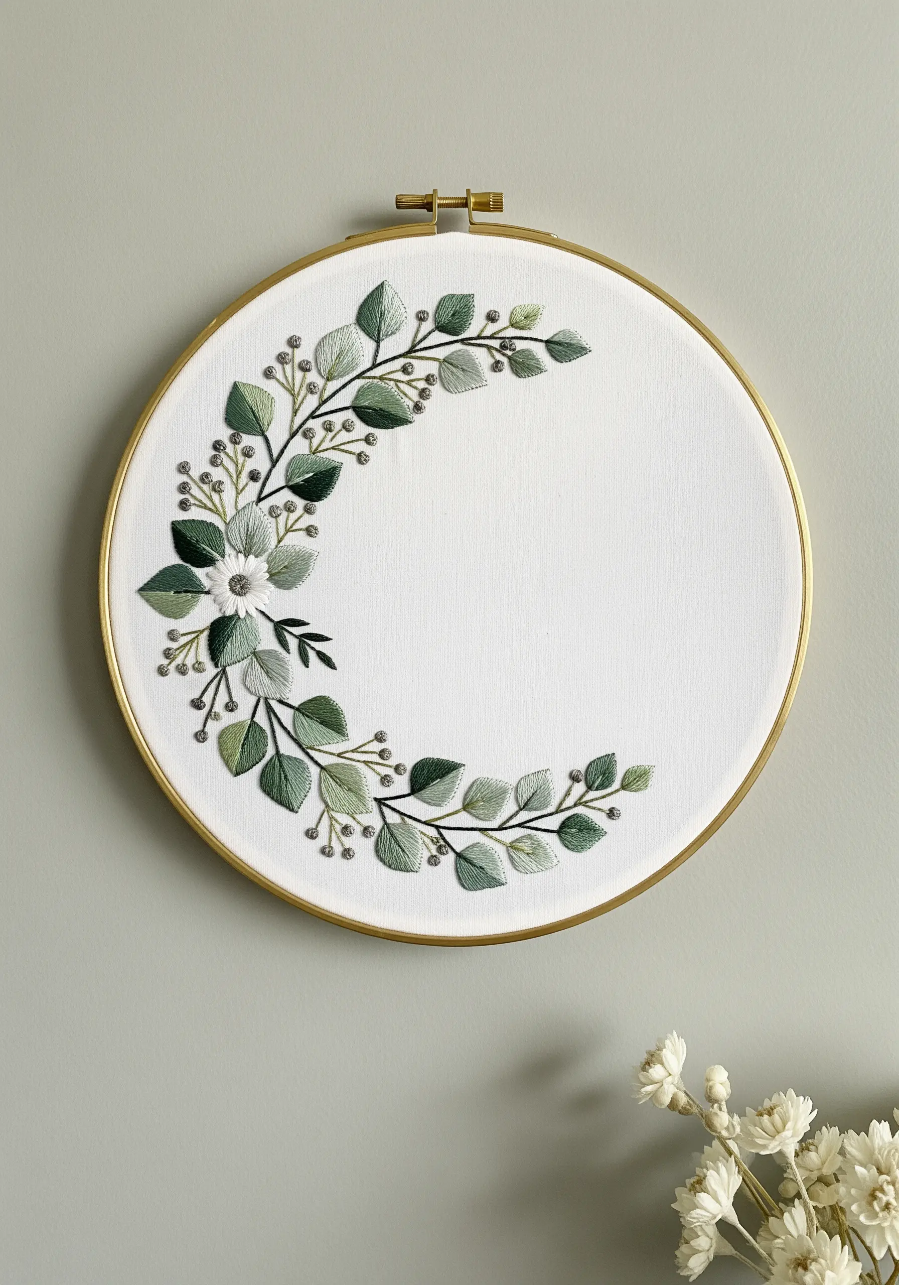 A modern crescent-shaped embroidery wreath of green leaves with tonal shading on white fabric.