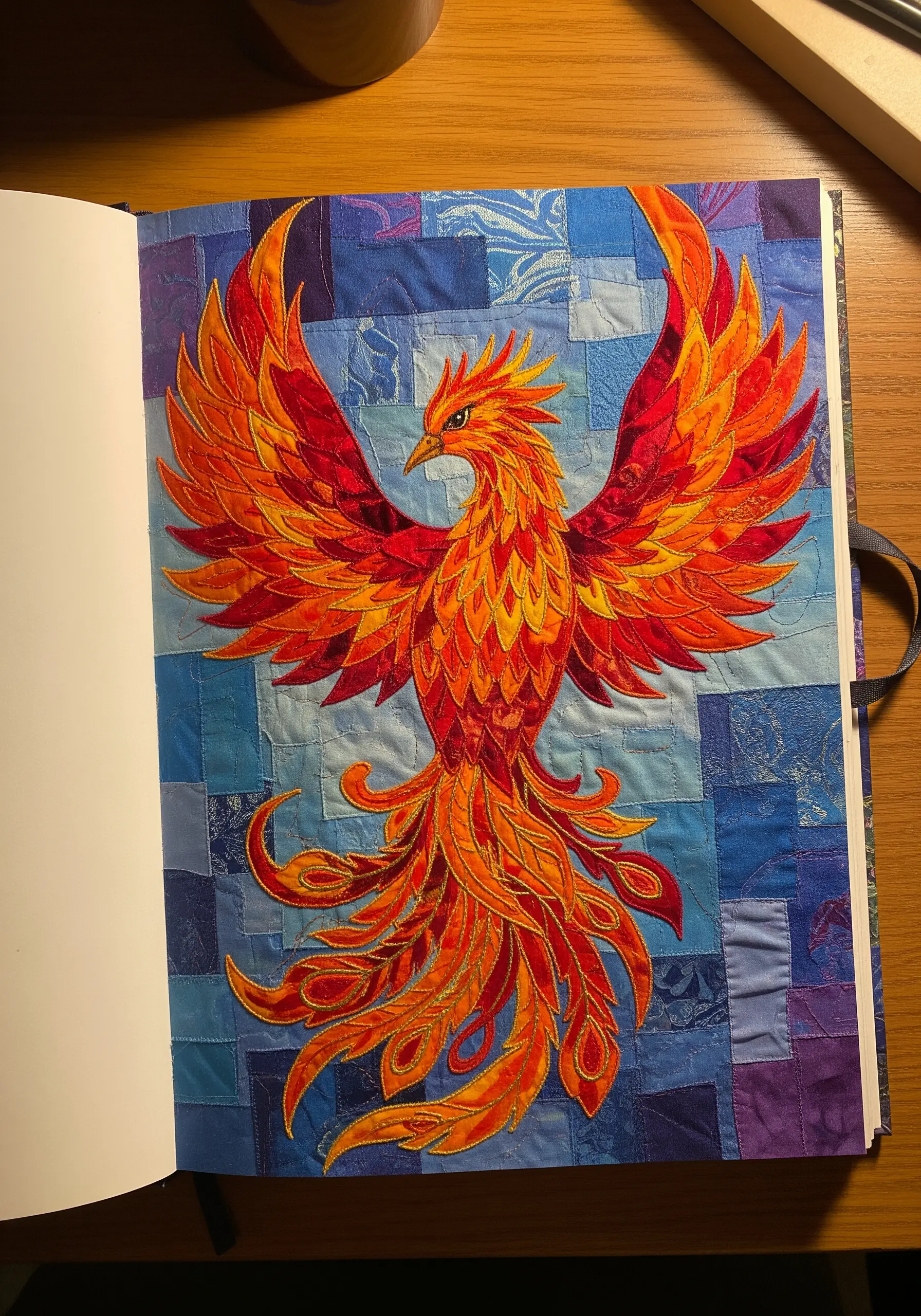 Intricate appliqué of a fiery phoenix with overlapping red, orange, and gold fabric pieces.