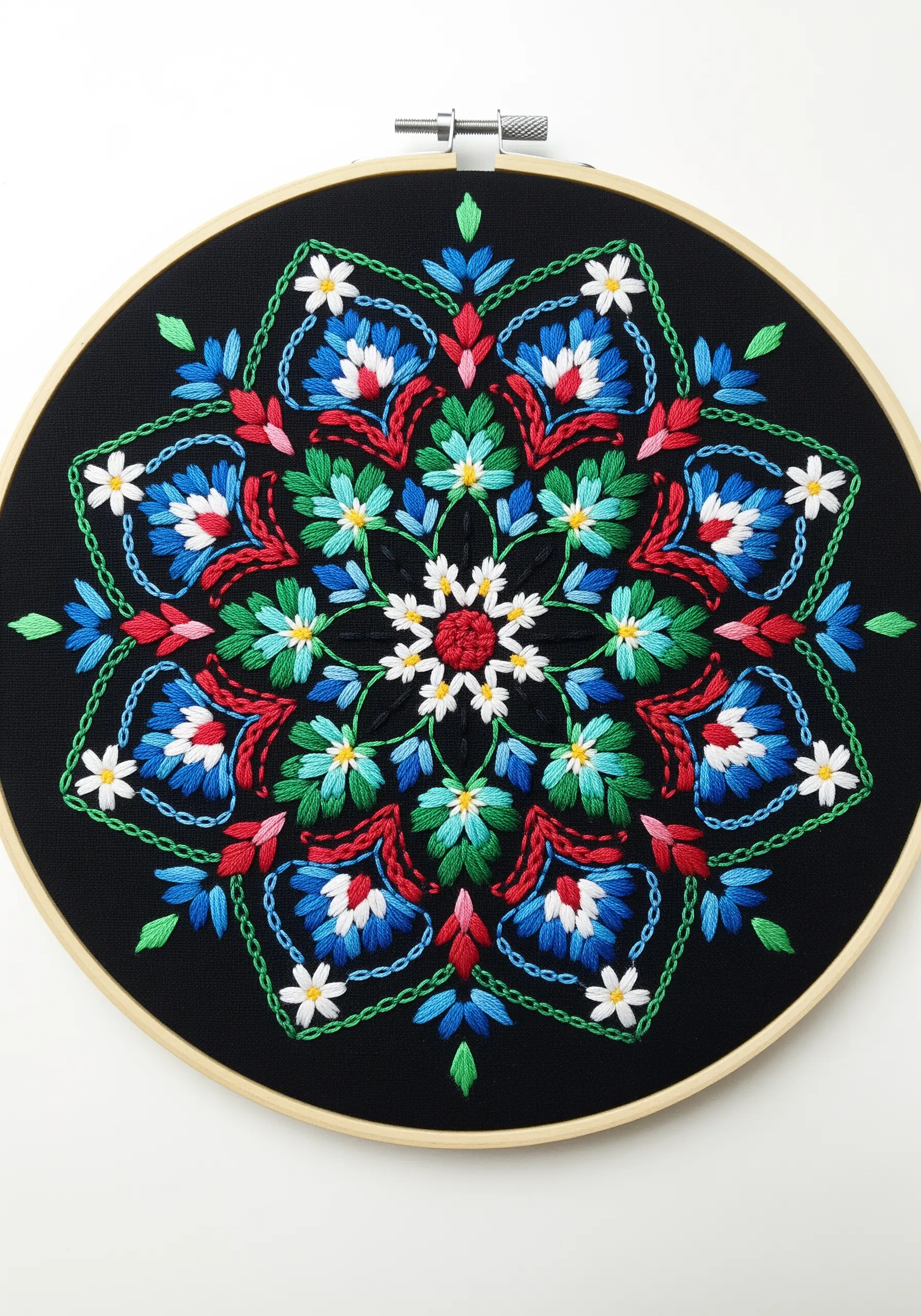 A vibrant, symmetrical floral mandala with blue, red, and green stitches on black fabric.