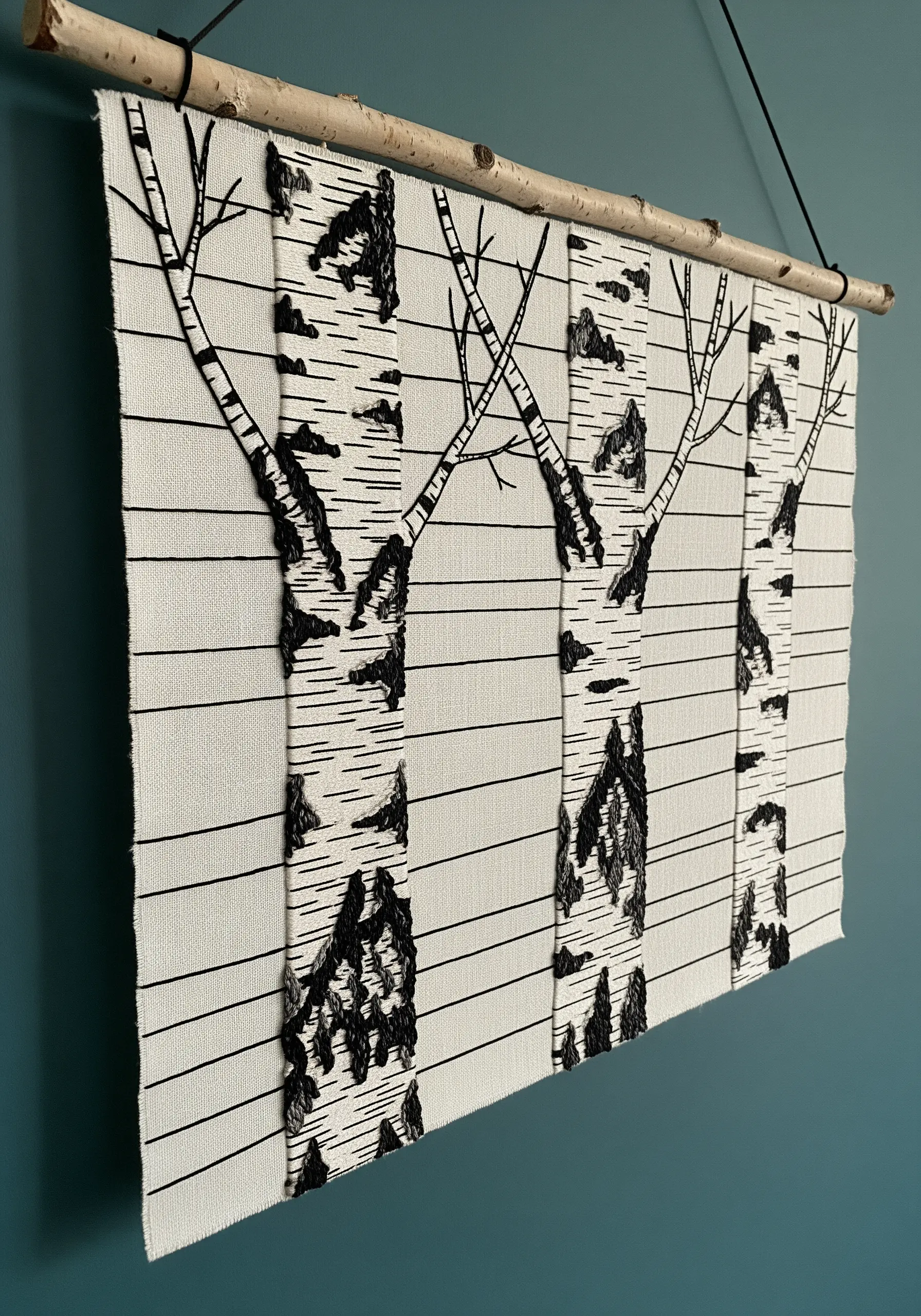 Wall hanging with appliquéd white fabric strips as birch tree trunks, detailed with black embroidery.